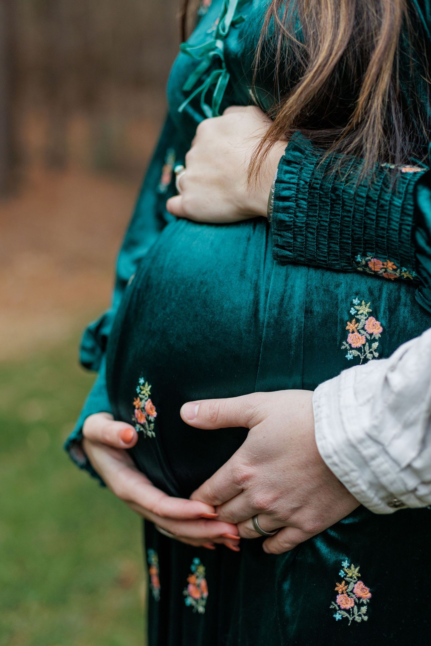 A young couple holding mom's pregnant belly outside in Williamsport, Pennsylvania