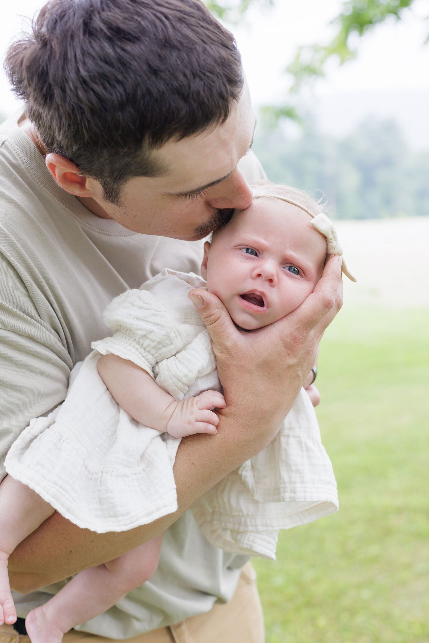 Dad kissing his newborn baby girl in a lifestyle newborn session in Lock Haven Pennsylvania
