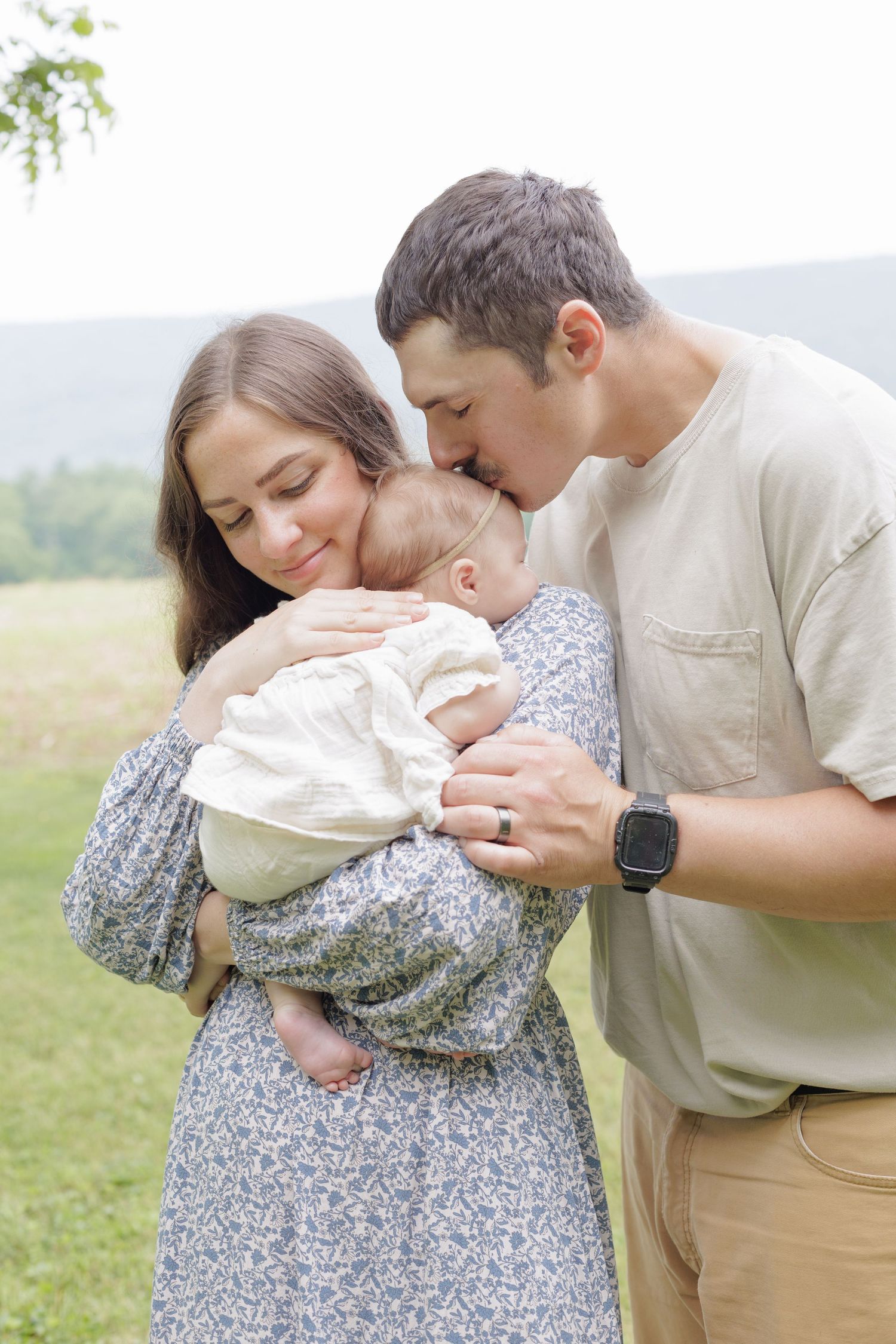 Mom and Dad are cuddling their newborn baby girl in a lifestyle newborn outdoor photography session in Lock Haven, Pennsylvania