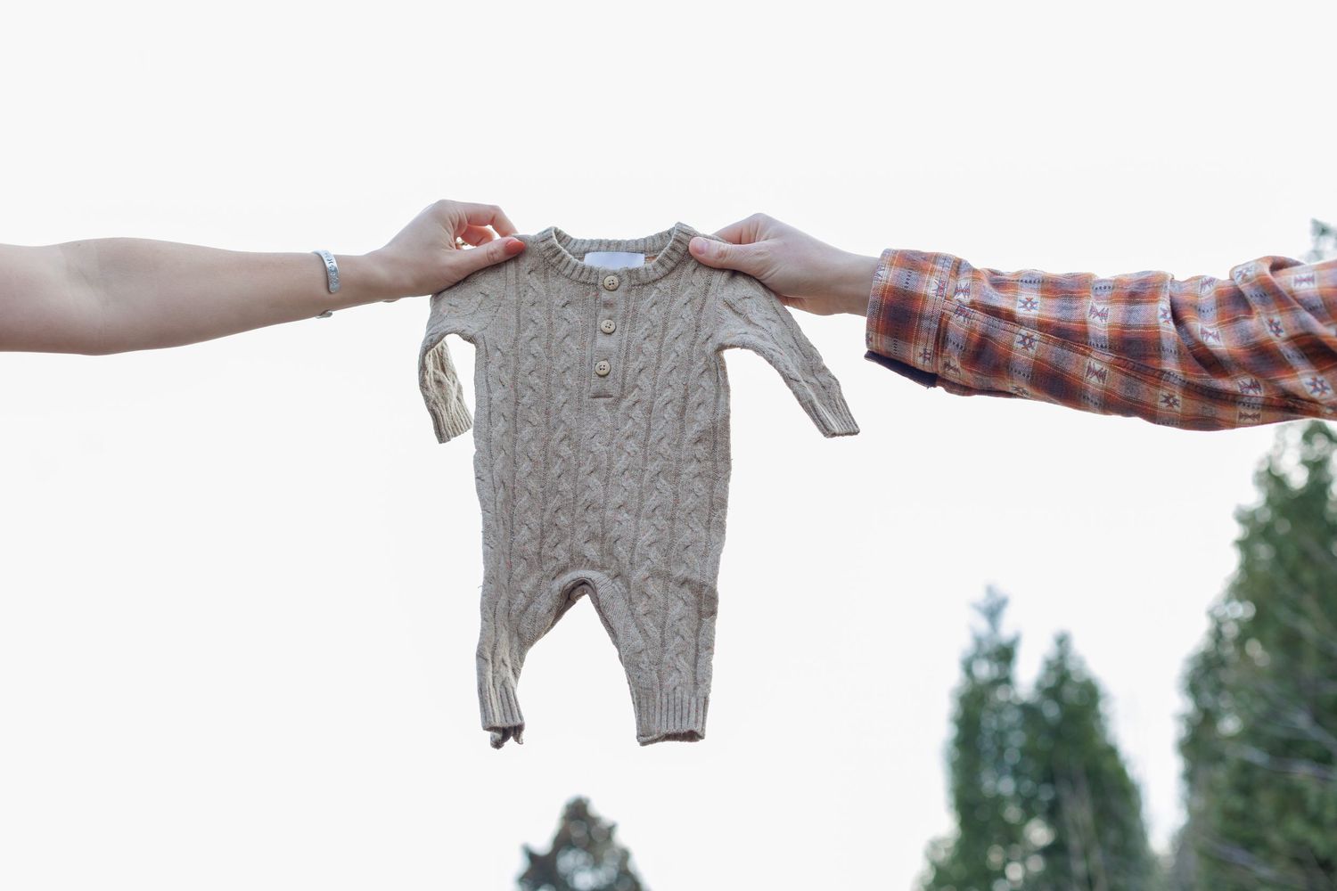 Mom and dad holding an outfit in the sky for their baby announcing preganancy in Williamsport Pennsylvania