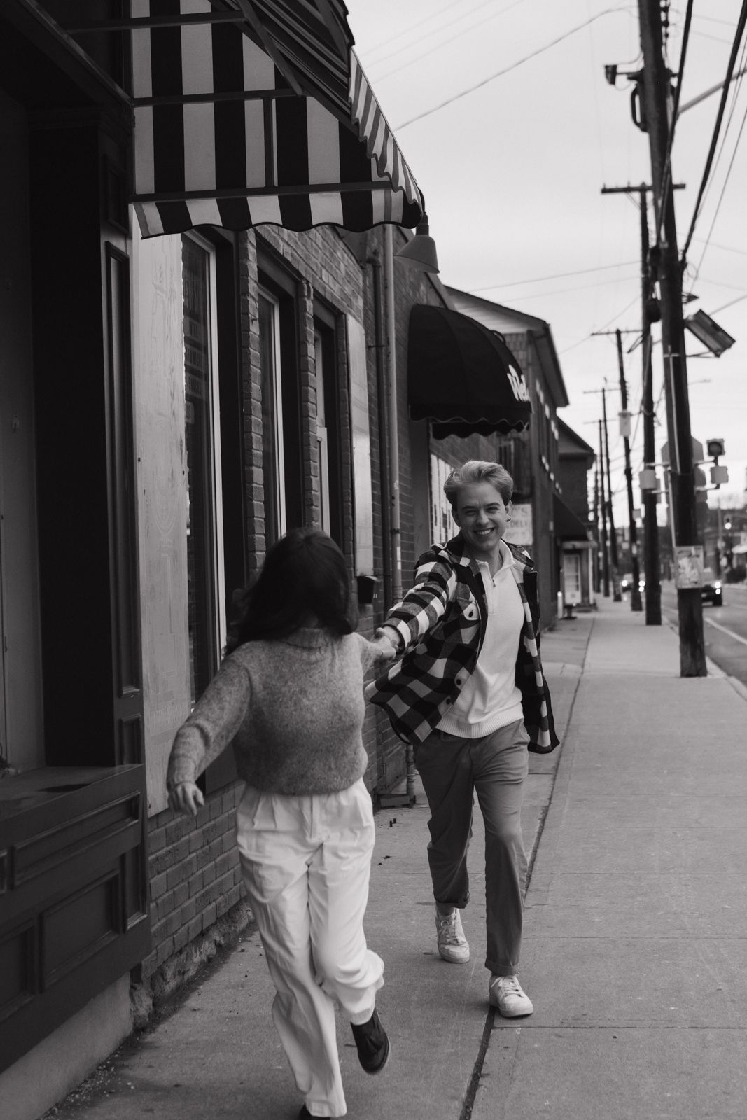 A candid black and white image of a couple running down the street together in Hamilton.