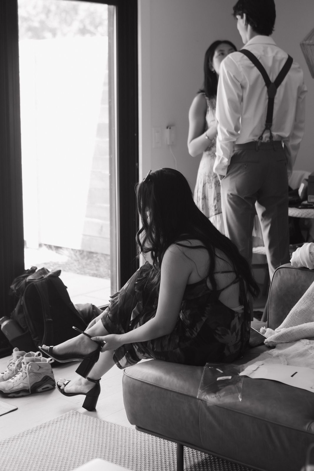 Black and white image of a woman putting her heels on in the getting ready suite on a wedding morning.