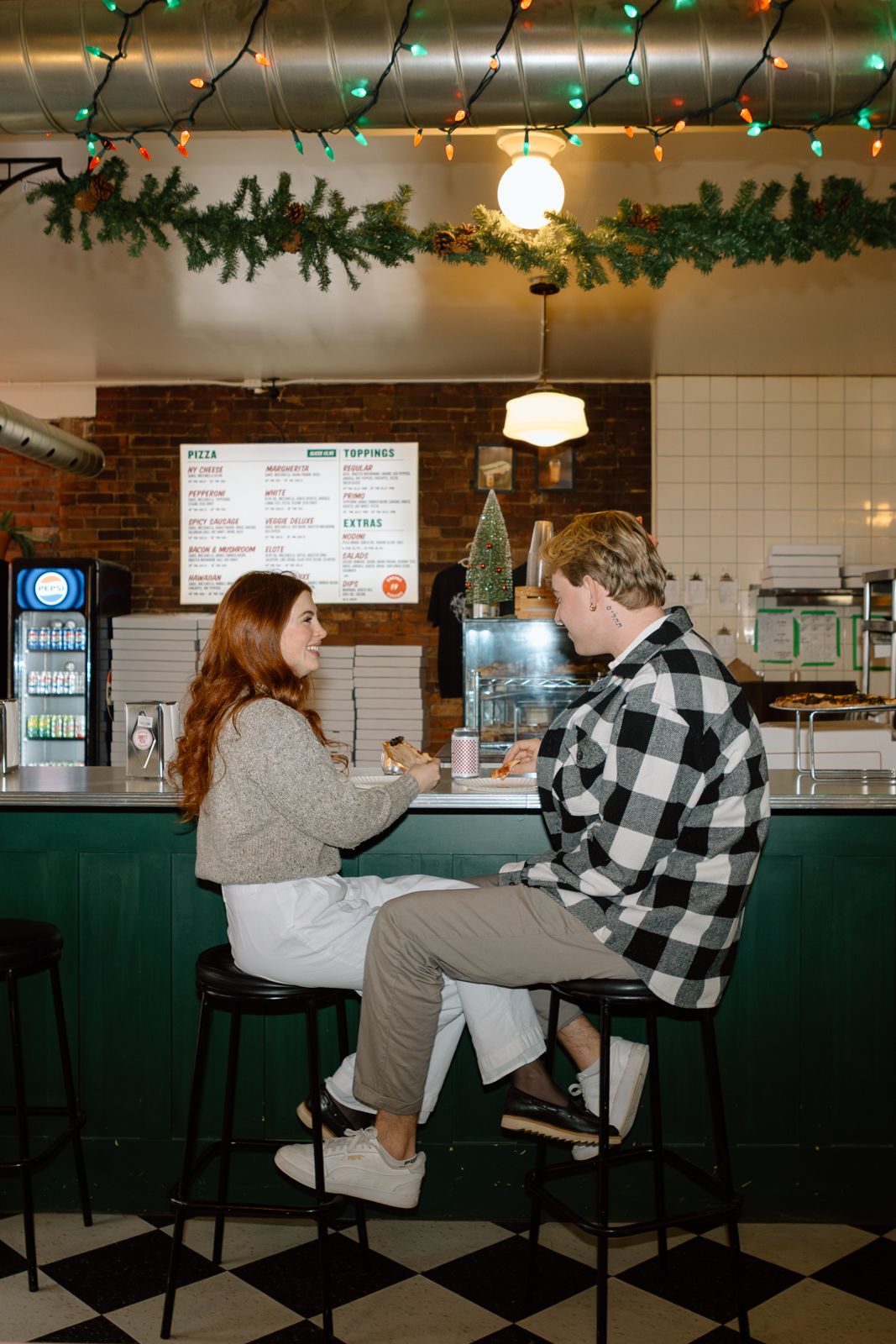 A couple sitting on barstools across from each other at a pizza parlour in Hamilton.