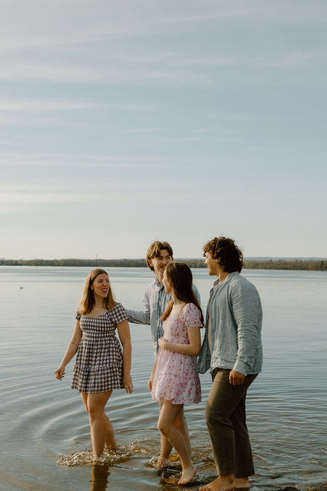 Group of four wading in a lake together at sunset.