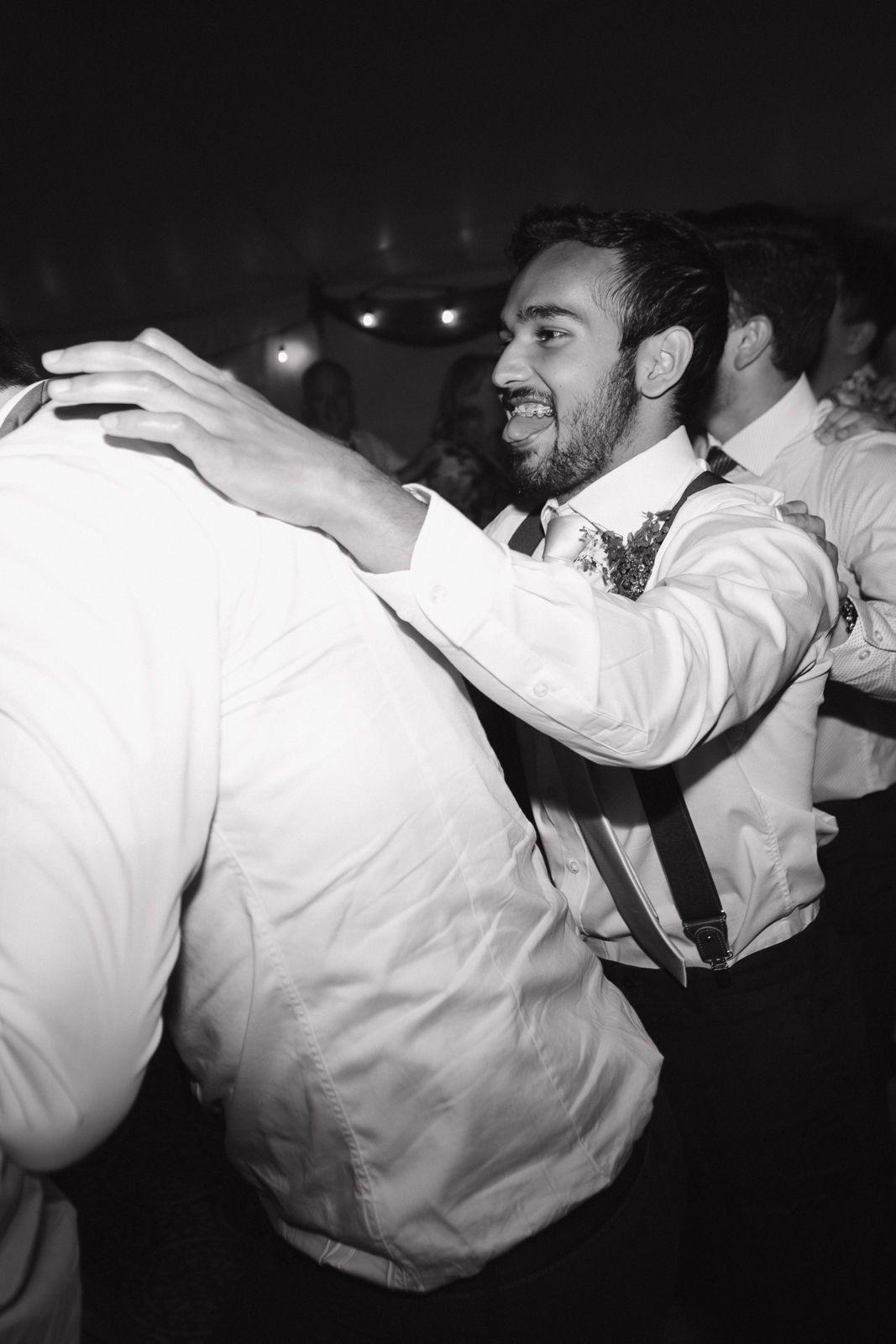 Candid black and white image of wedding guests in a dance train at a wedding reception.