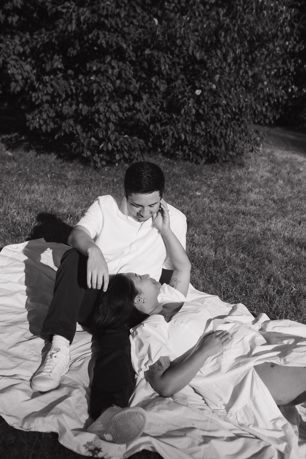 Couple lounging on a picnic blanket together.