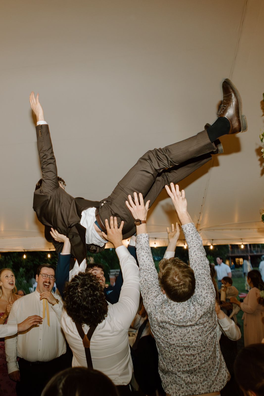A groom gets thrown into the air on the dance floor at a wedding reception.