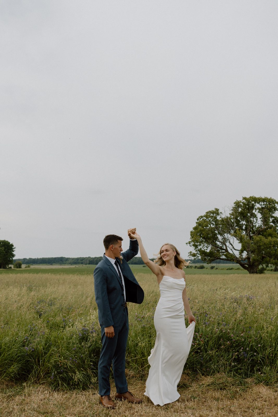 Bride and groom dancing together in a field.