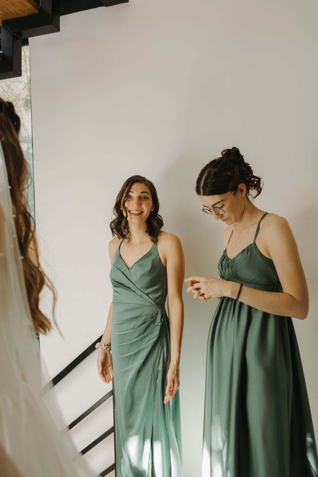 Candid moment of two bridesmaids smiling at a bride all dressed up on a wedding morning.