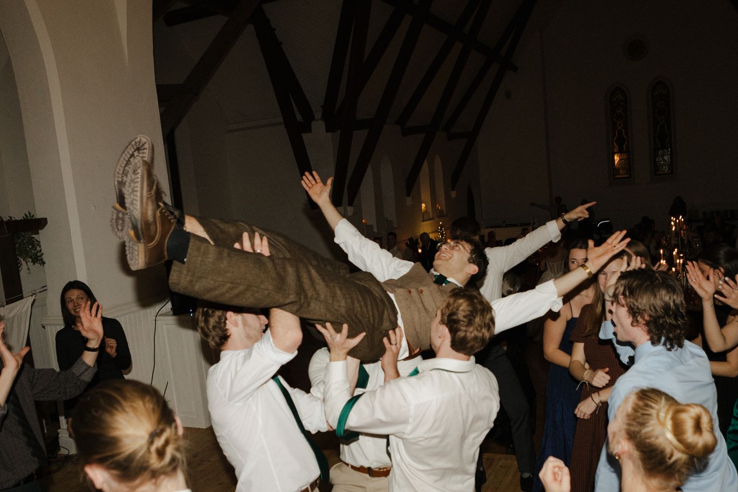 A photo of a groom crowdsurfing at a wedding reception.
