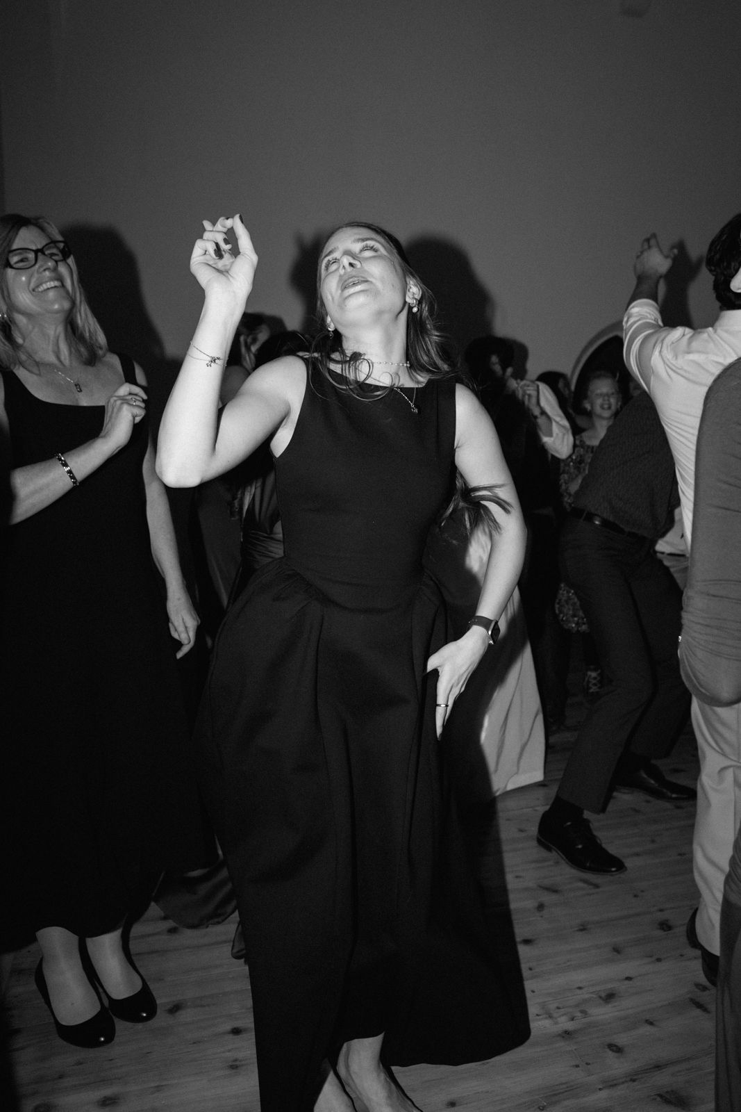 A black and white photo of a woman dancing at a wedding reception.