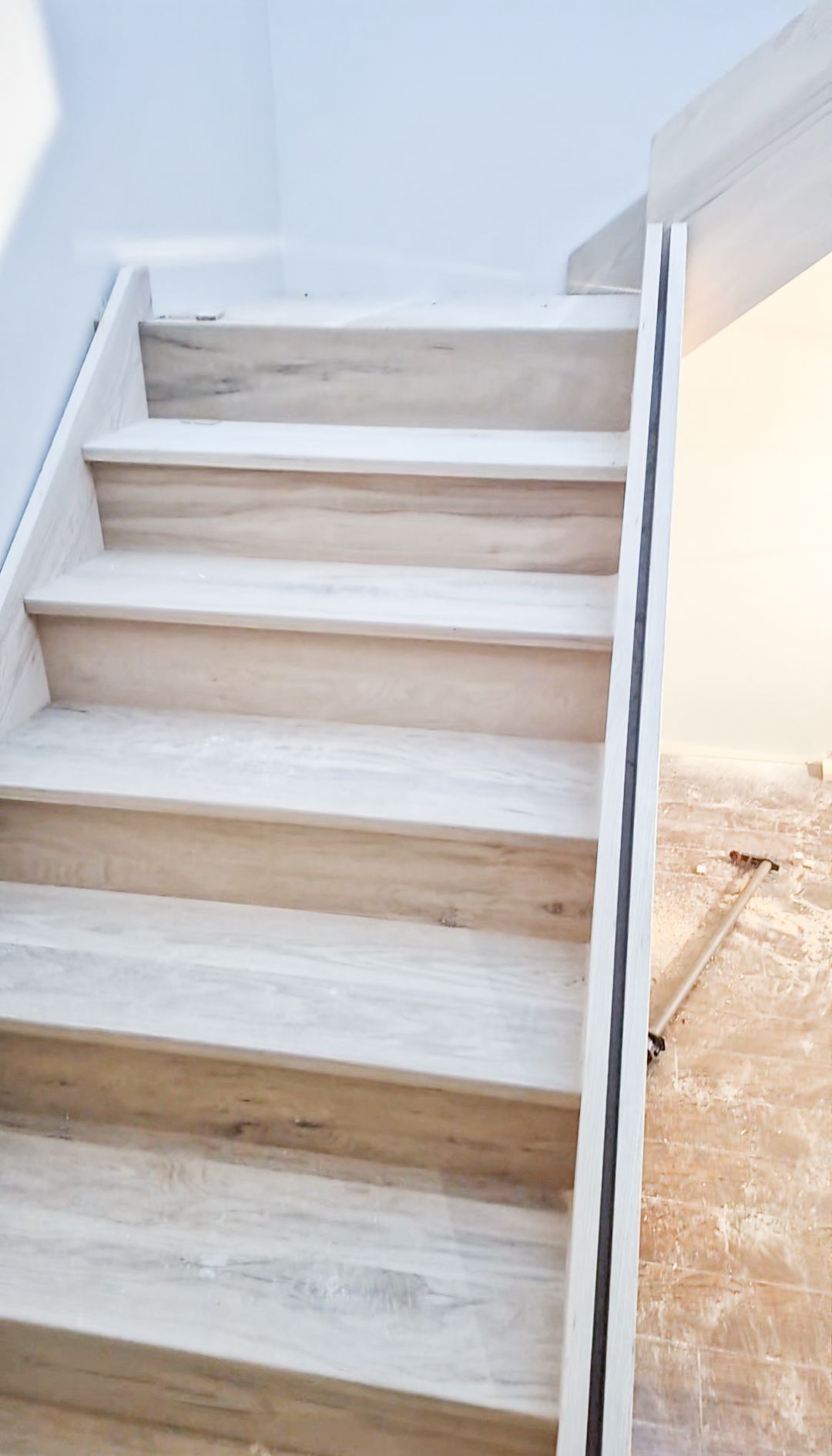 Modern luxury staircase with wooden risers and sleek minimalist design during installation.