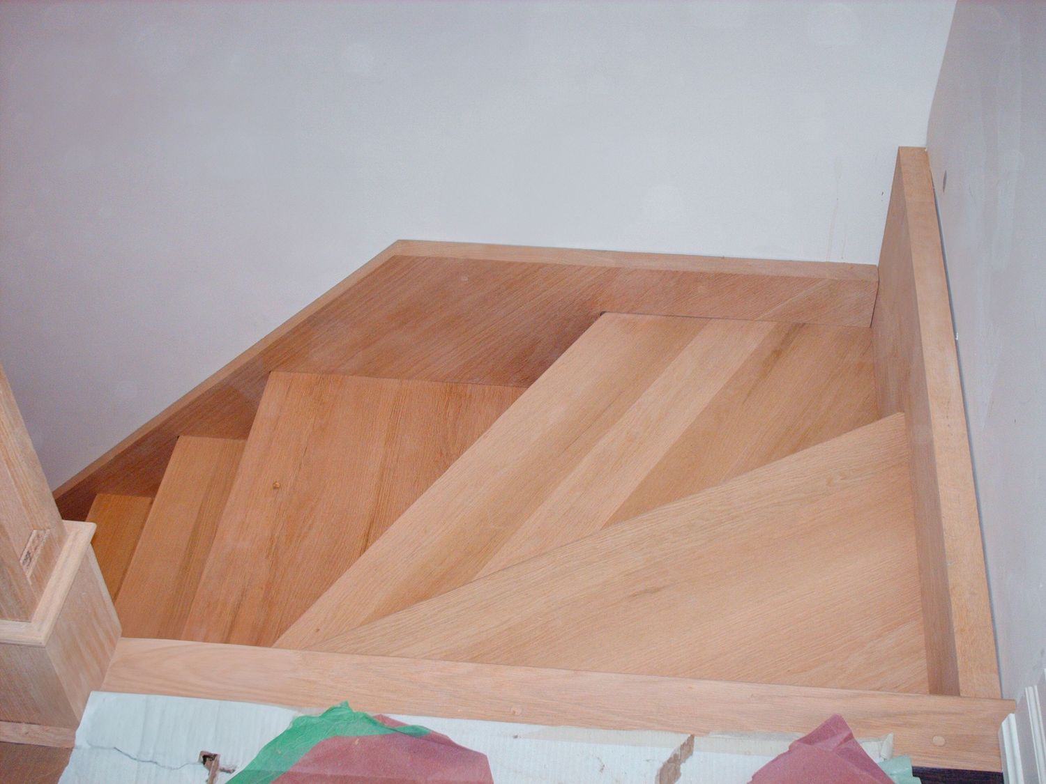 Aerial view of light wood staircase with winder steps during residential construction and installation.
