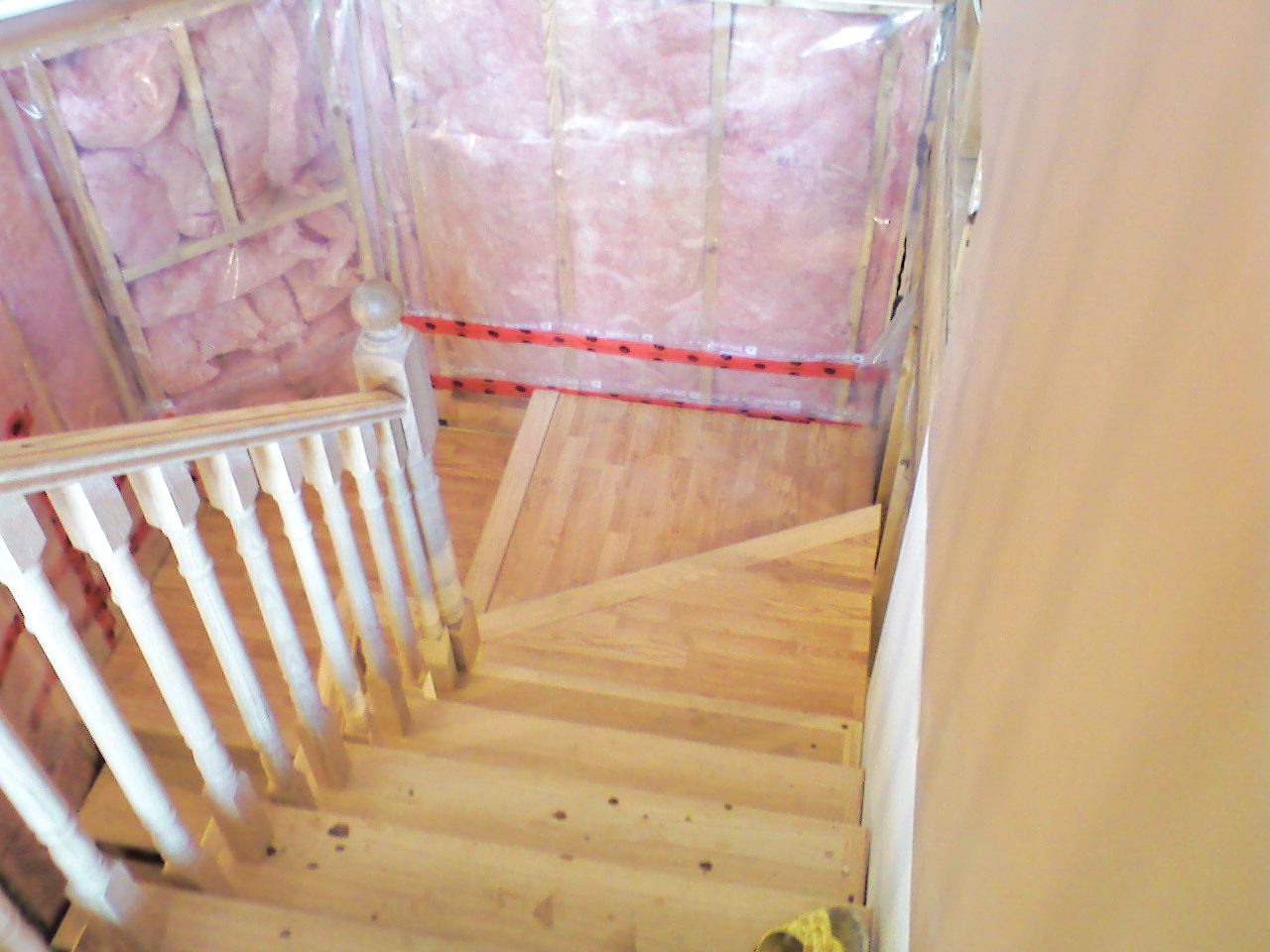 Top-down view of wooden staircase with white balusters during home renovation.