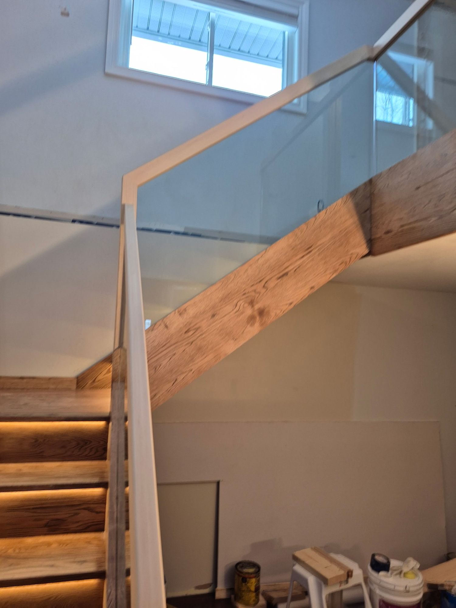 Oak staircase with glass railing and wooden handrail featuring  LED accent lighting.