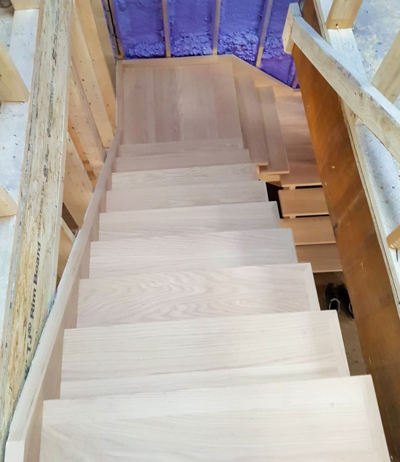 Top-down view of unfinished oak staircase with clean treads and risers during construction.