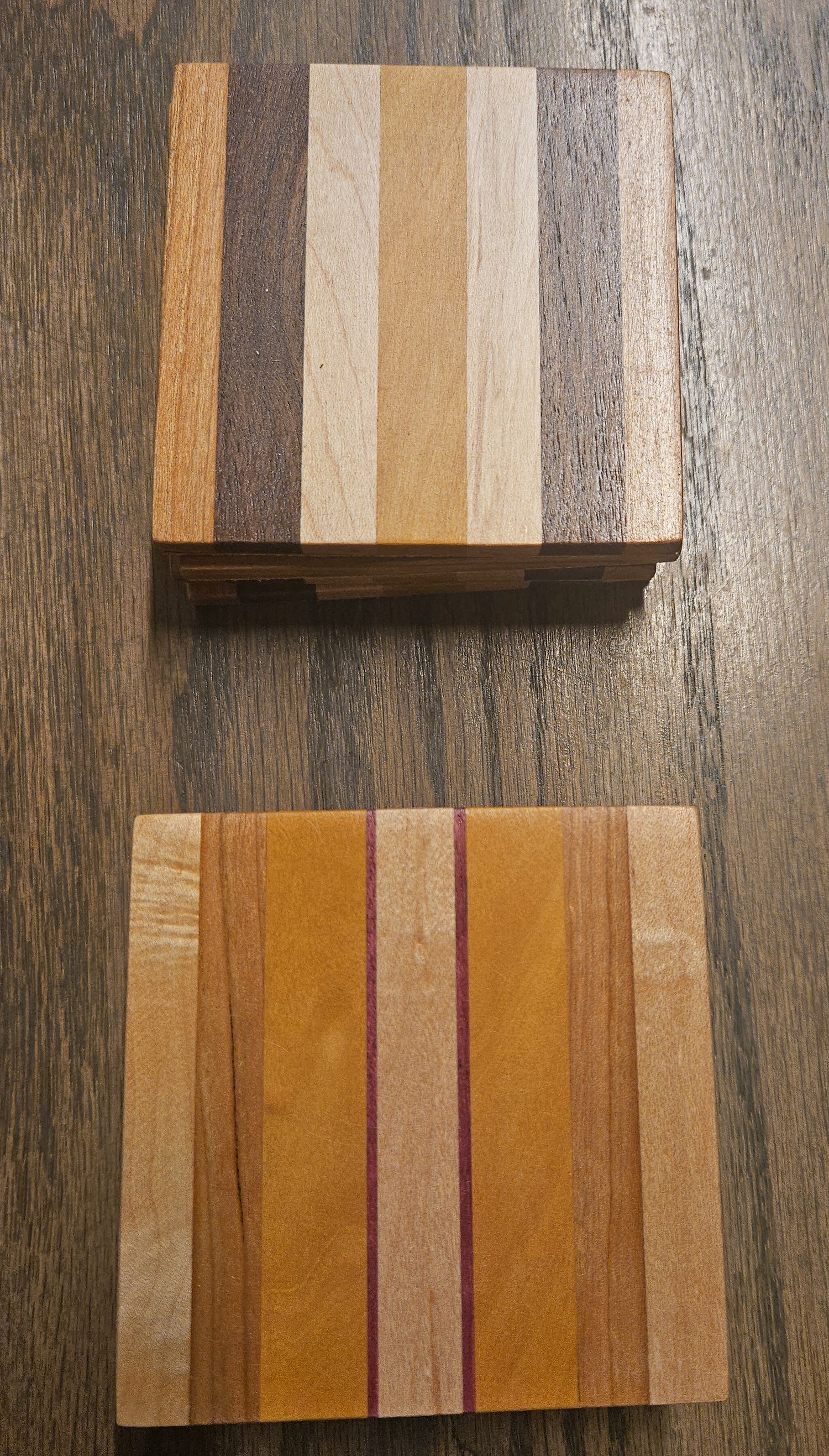 Set of handmade striped wood coasters in mixed walnut, maple, and cherry wood tones.
