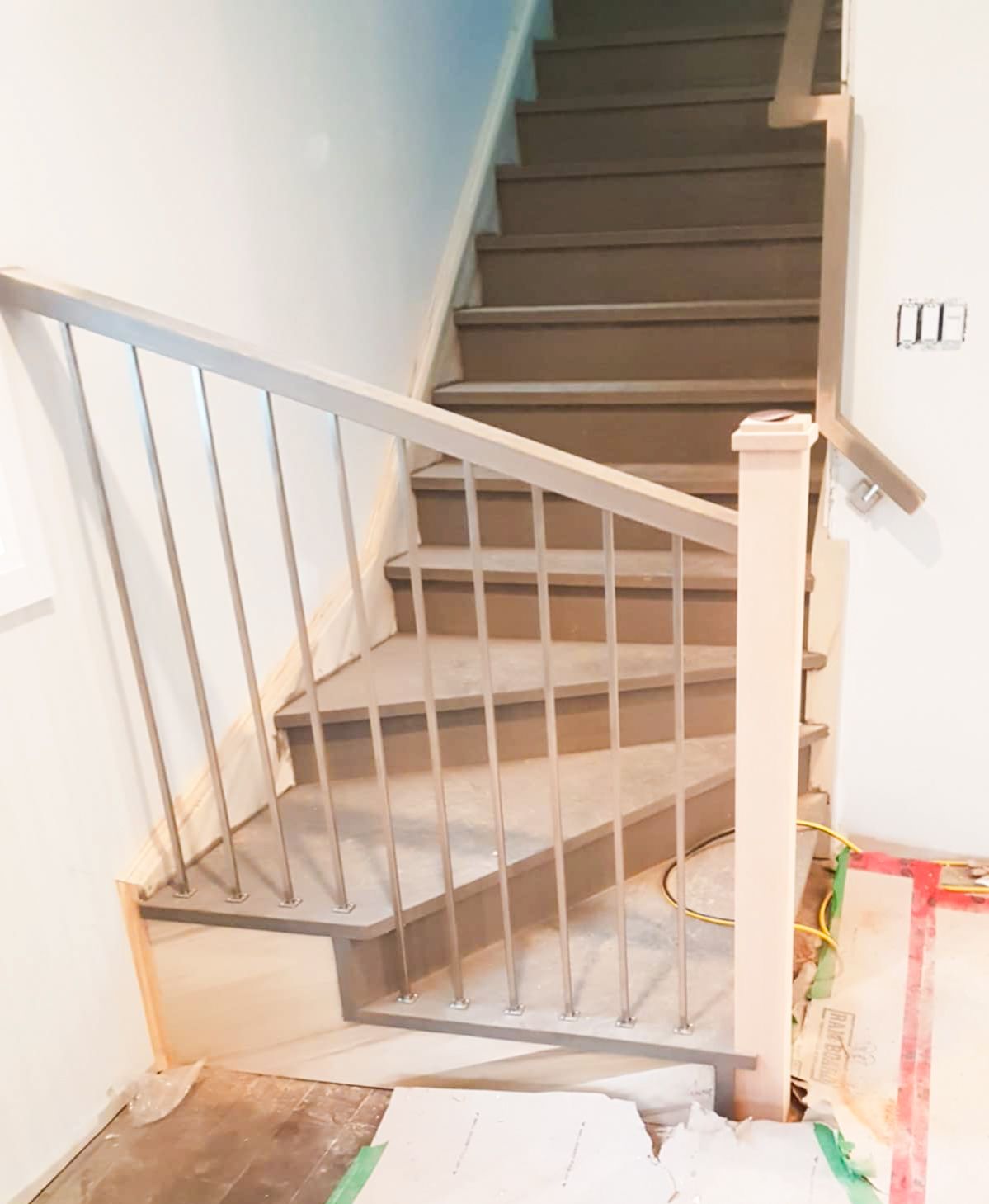 Newly installed winder staircase with stainless steel pickets in a home under renovation.
