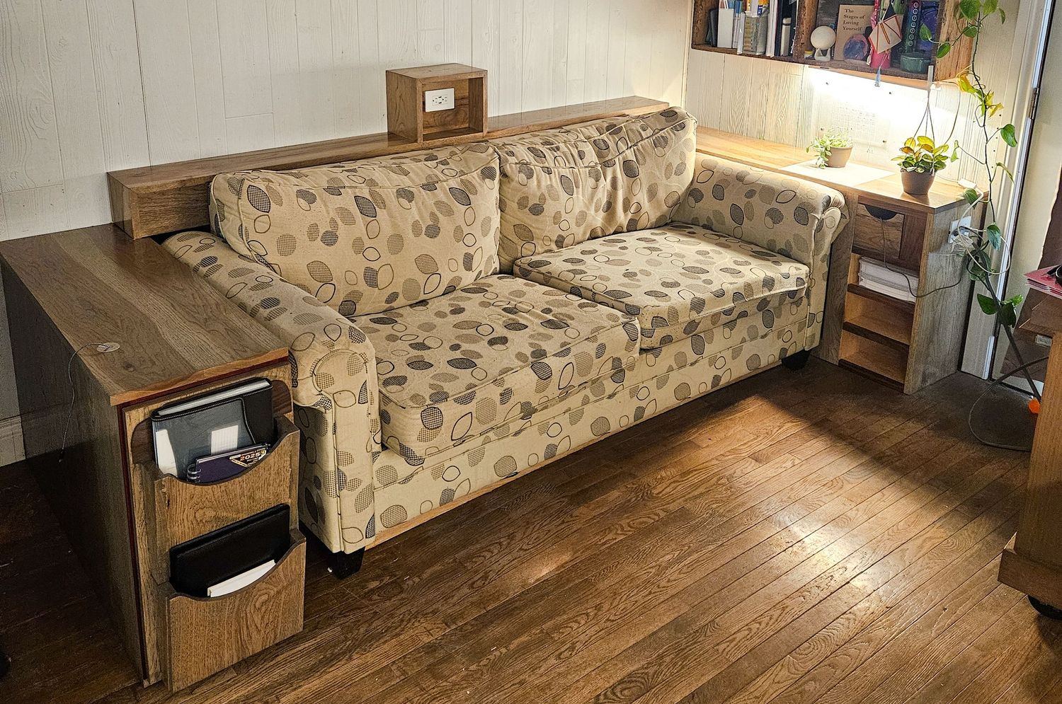 Custom wooden sofa surround with built-in shelving and storage with build in electrical plugs.