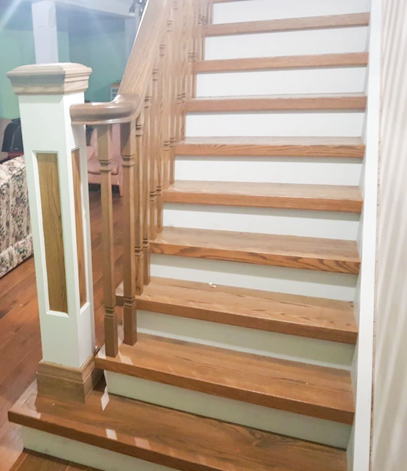 Renovated staircase with oak wood treads, white risers, and decorative newel post in a home.
