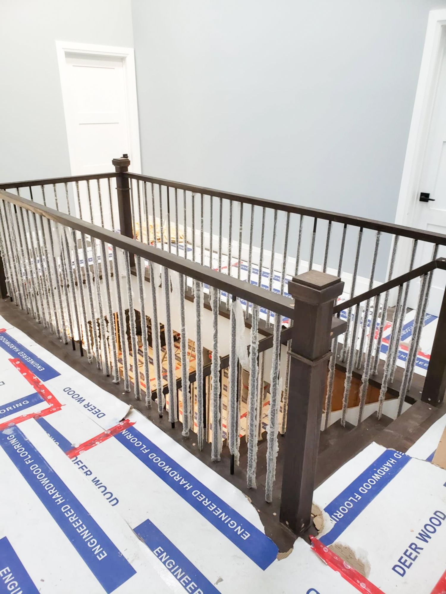 Dark wood stair railing with metal balusters on upper landing.