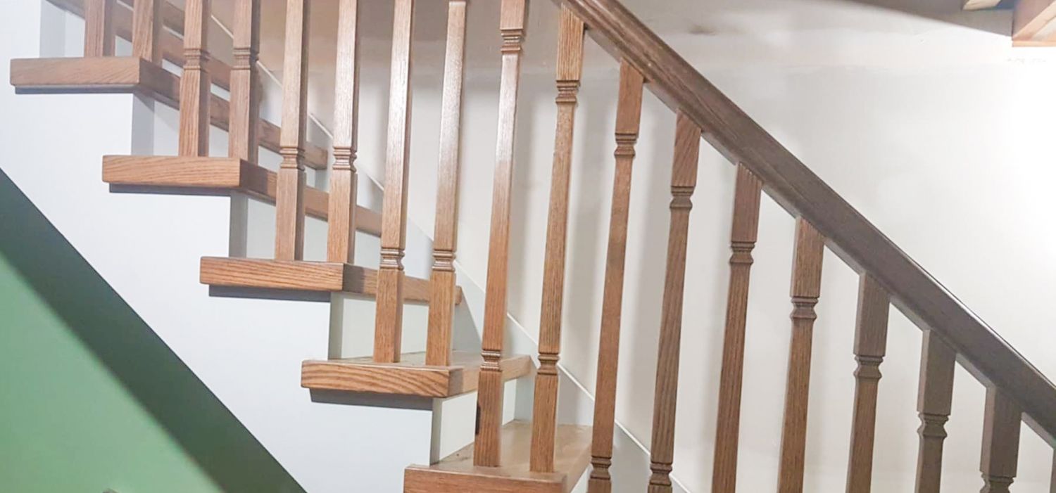 Classic wooden staircase with turned baluster spindles and oak handrail in a residential home interior.