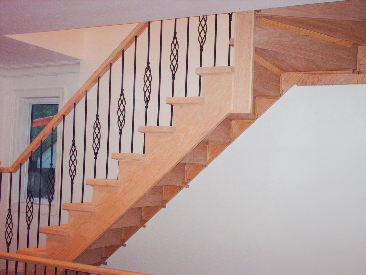 Completed light oak staircase featuring alternating plain and decorative metal spindles.