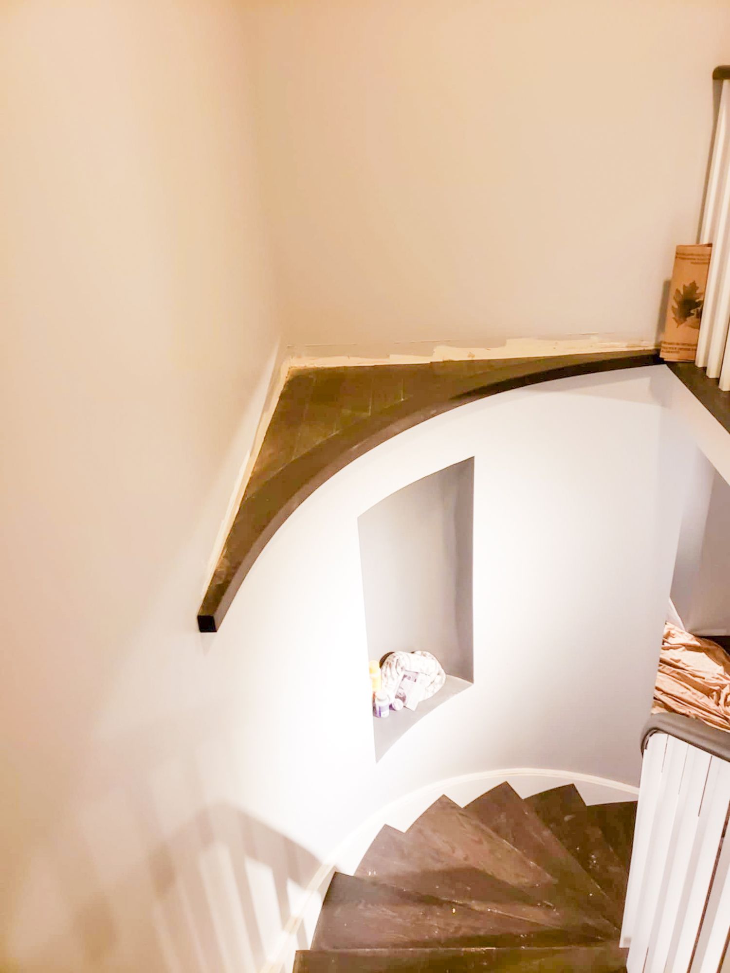 Aerial view of curved staircase with dark handrail and white walls in a home renovation recap project.