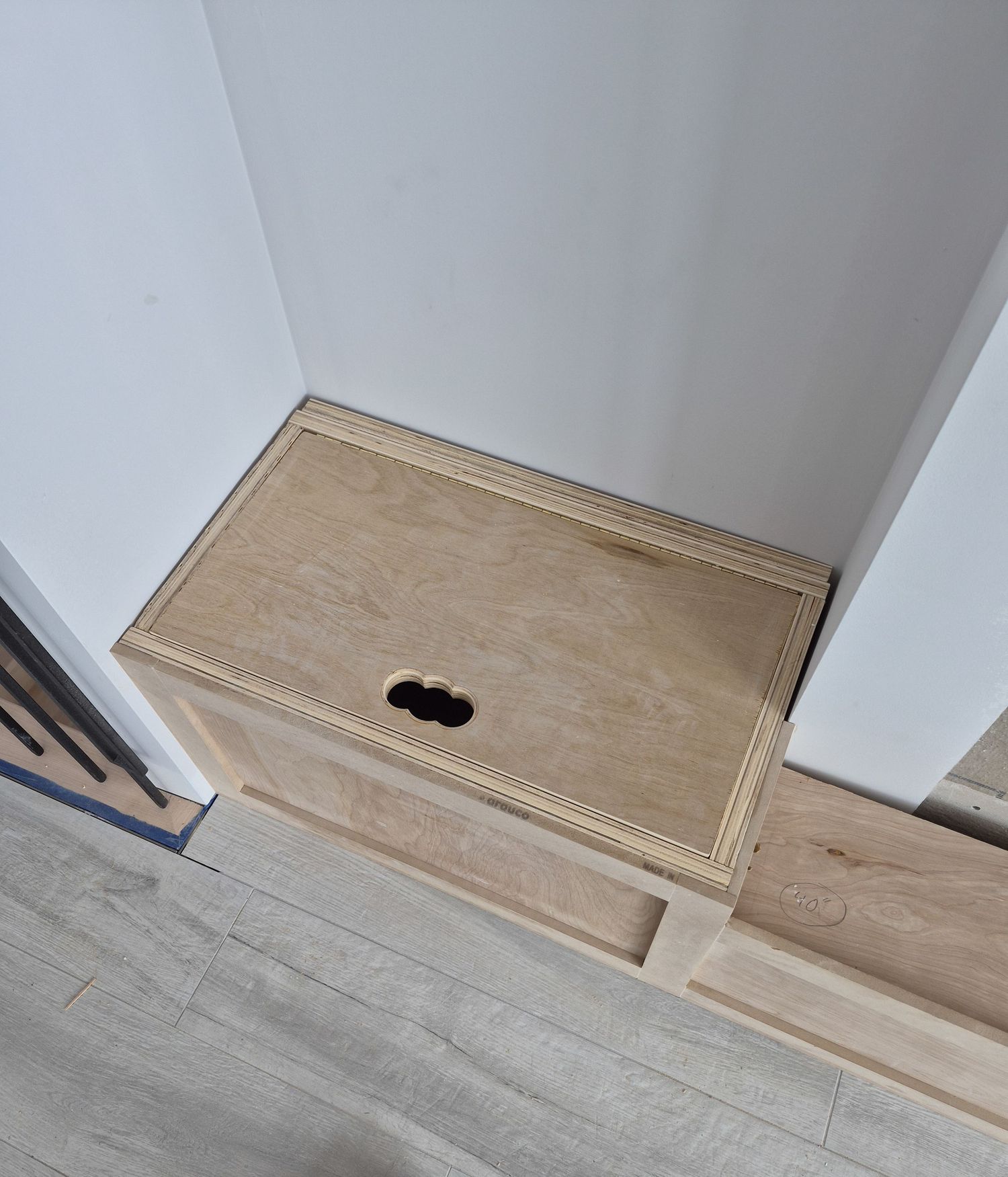 Handcrafted wooden storage box with finger-hole lid cutout installed beside a fireplace hearth.