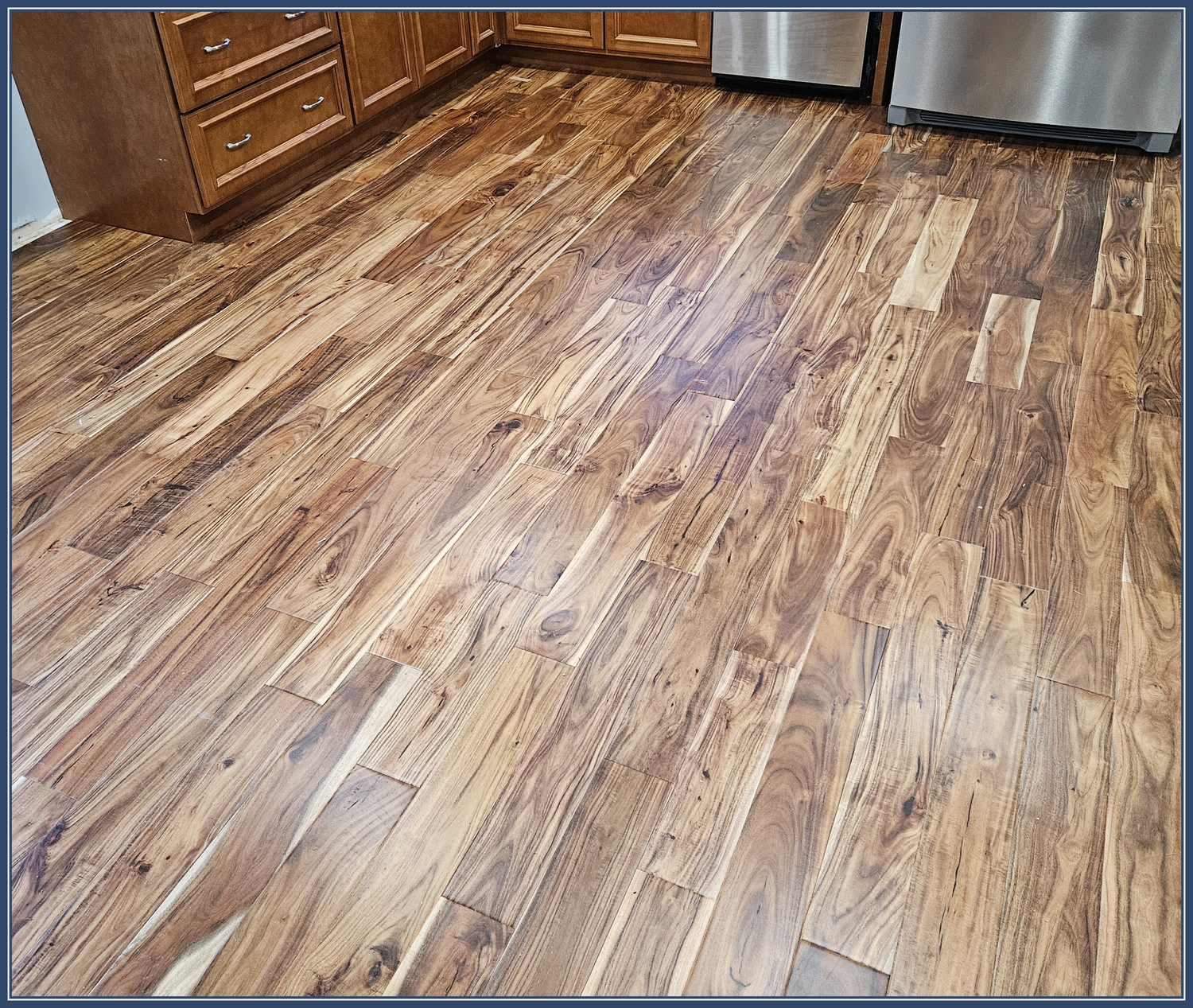 Beautiful acacia wood flooring with rich grain patterns and warm tones in a kitchen setting.