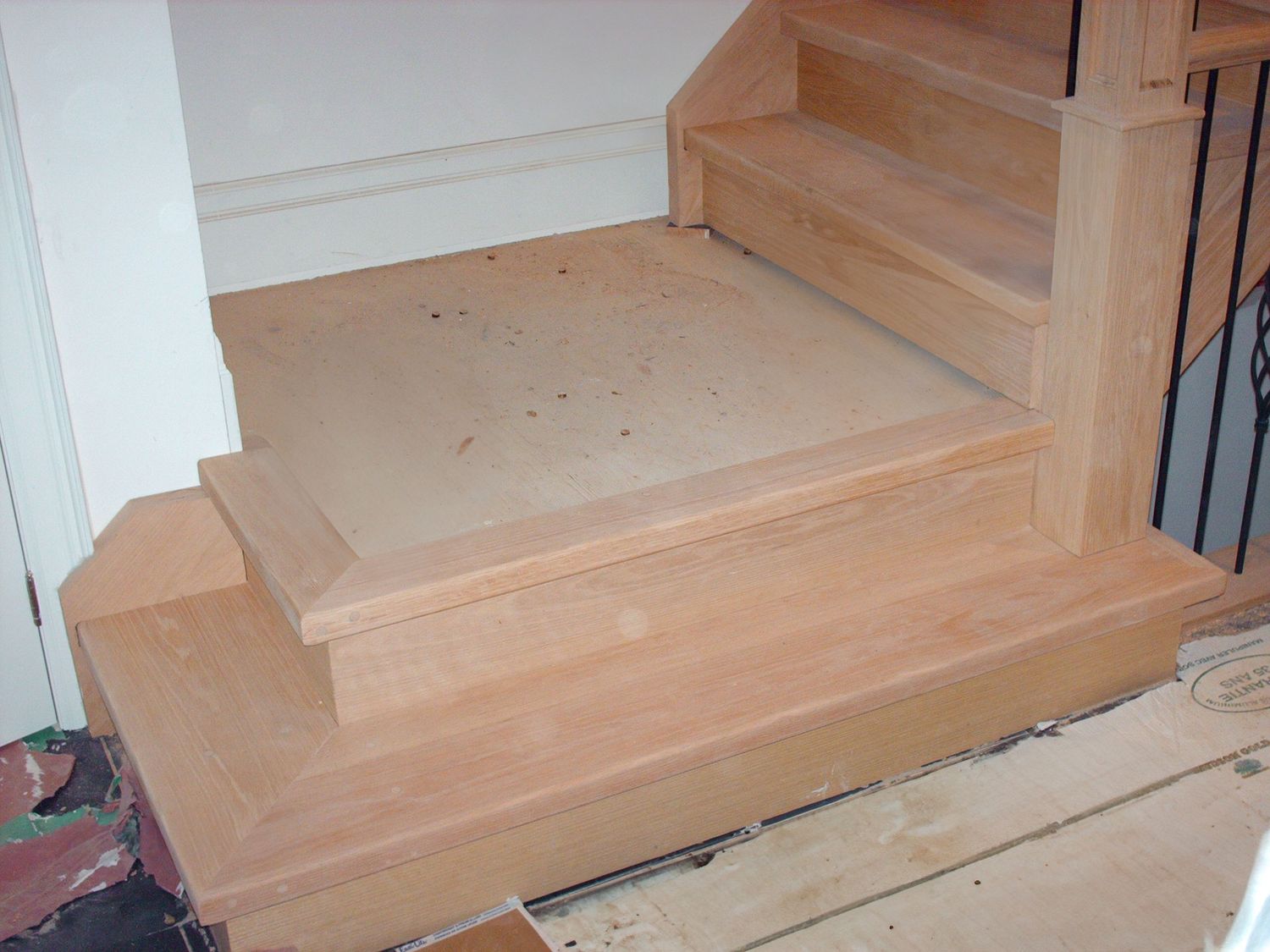 Close-up of freshly installed light wood stair treads and risers with bullnose bottom step detail.