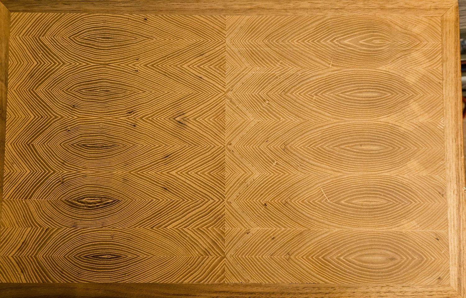 Top view of a solid ash wooden cutting board featuring a stunning book-matched grain patterns.