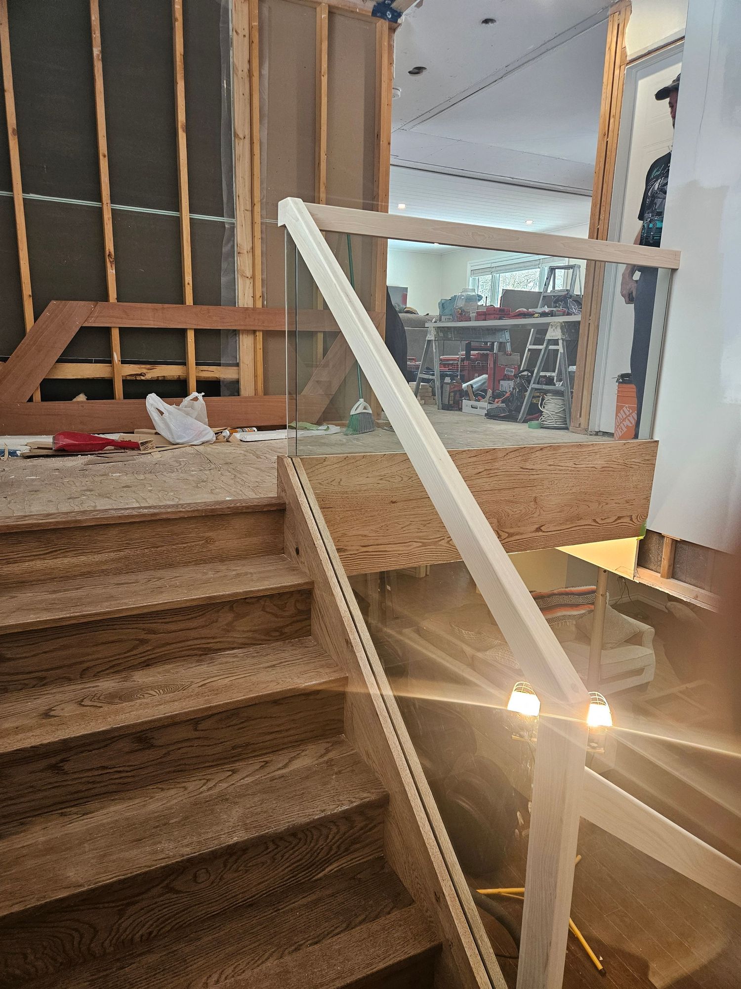 Oak stair treads with glass railing and wooden handrail during home renovation.