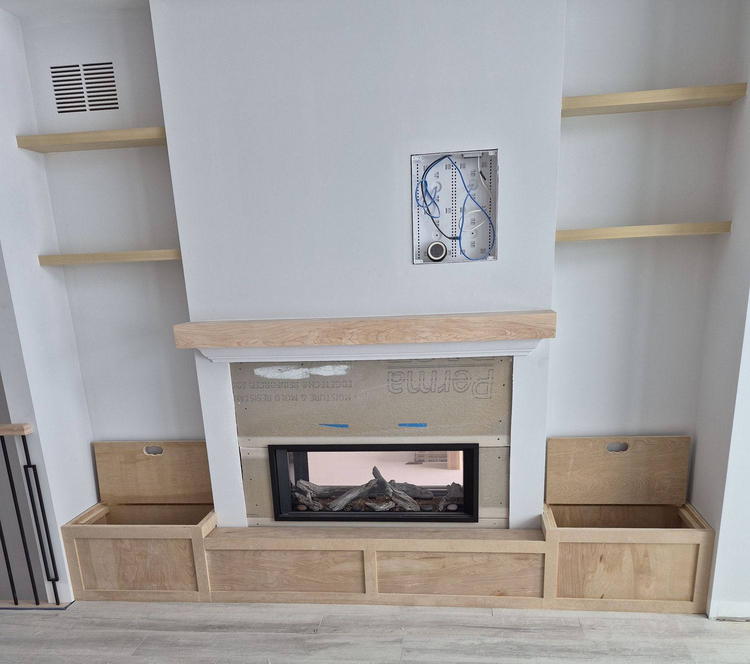Custom built-in fireplace surround with floating shelves and wooden storage bench cabinets.
