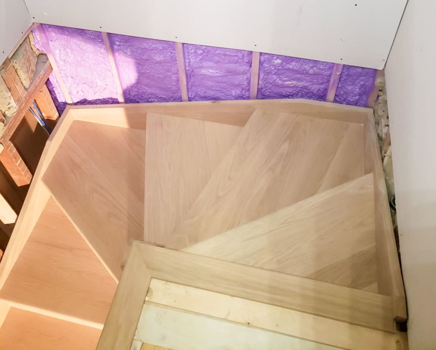 Top-down view of light wood winder staircase during home construction.