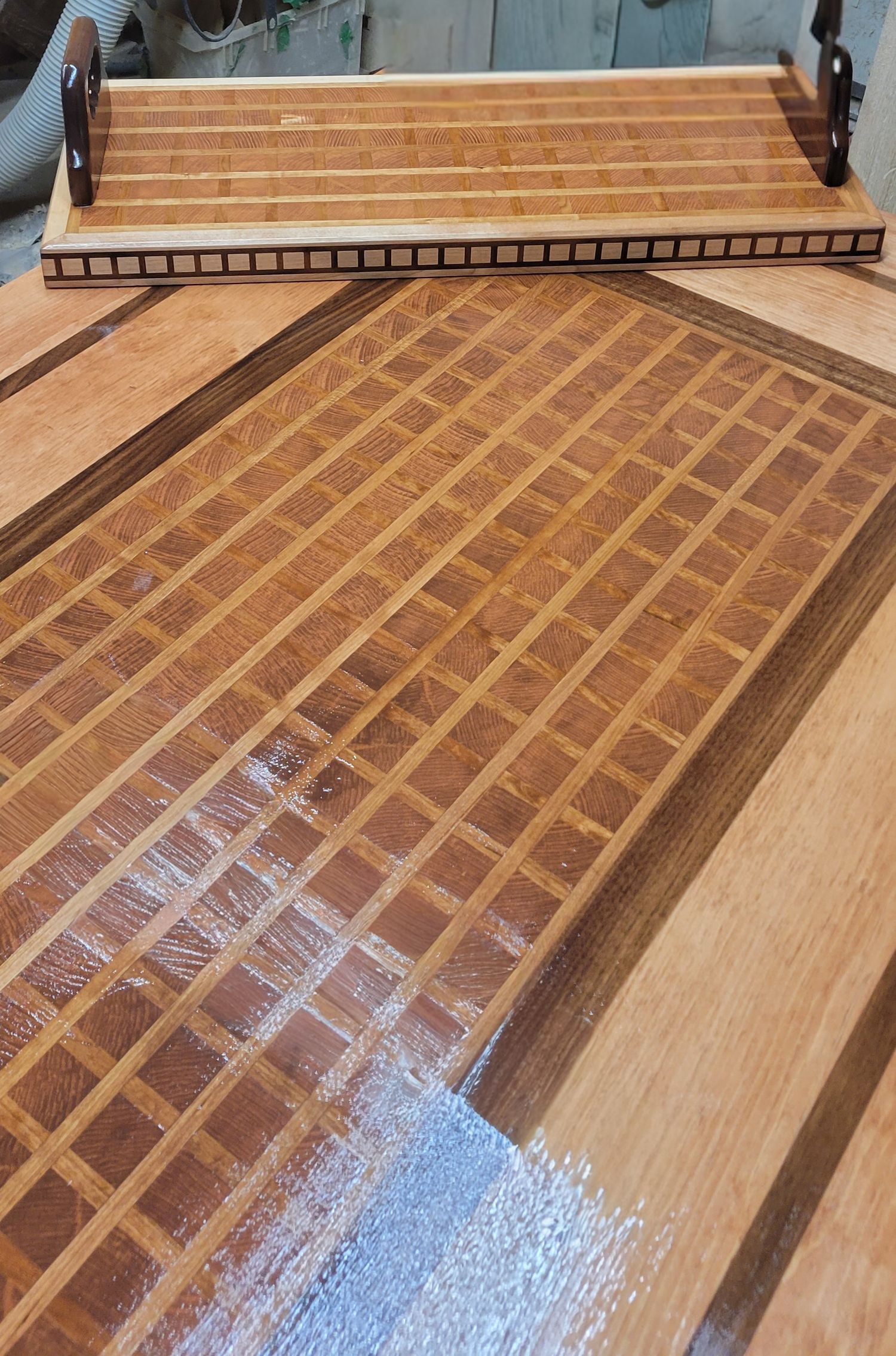 Close-up of handcrafted wood table featuring grid pattern inlay centerpiece with decorative border detail.