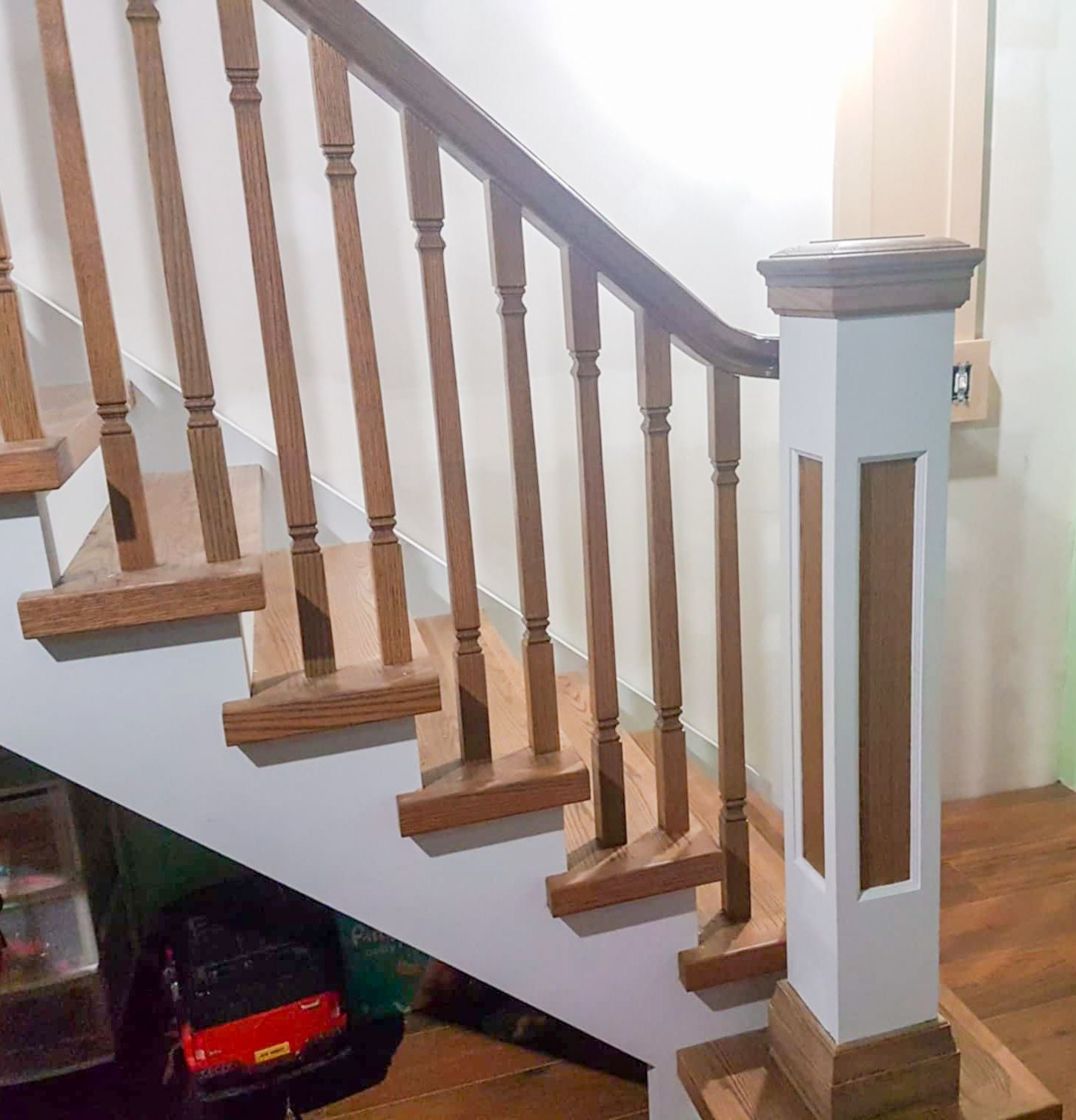 Elegant wooden staircase with turned oak balusters, white painted risers, and decorative newel post in a home interior.