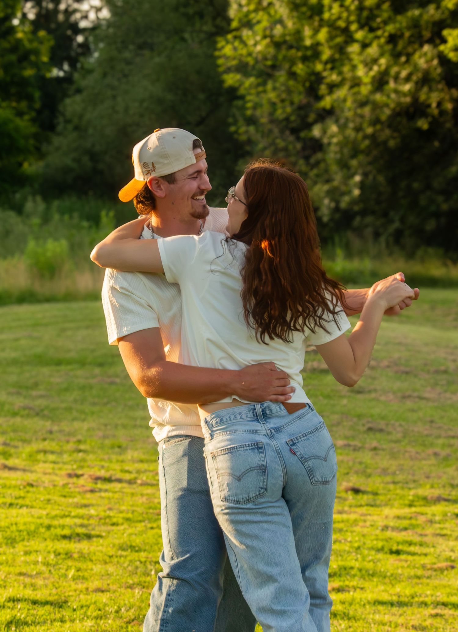 Couple embracing in a sunny field during an outdoor couples session.
