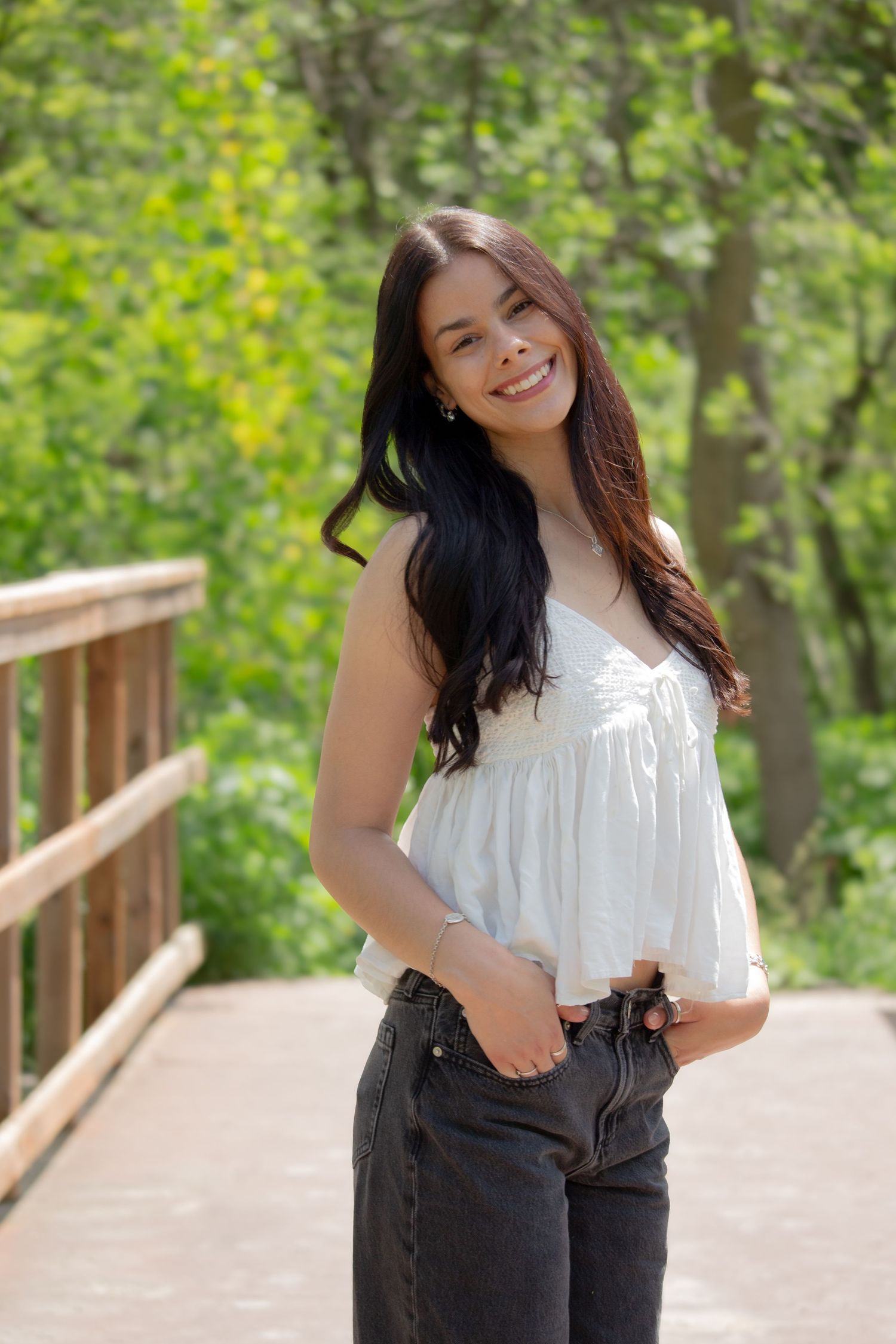 Young woman portrait session posing on a bridge surrounded by beautiful greenery.