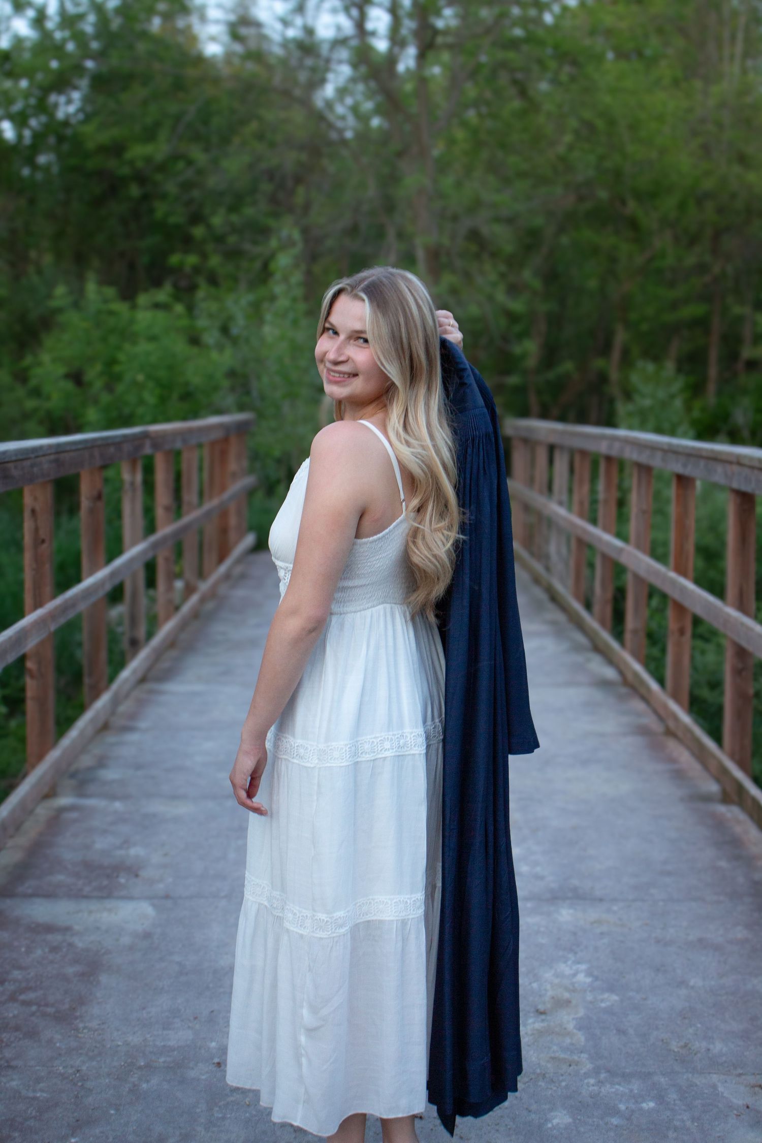 Graduate posing on a wooden bridge during an outdoor photography session.
