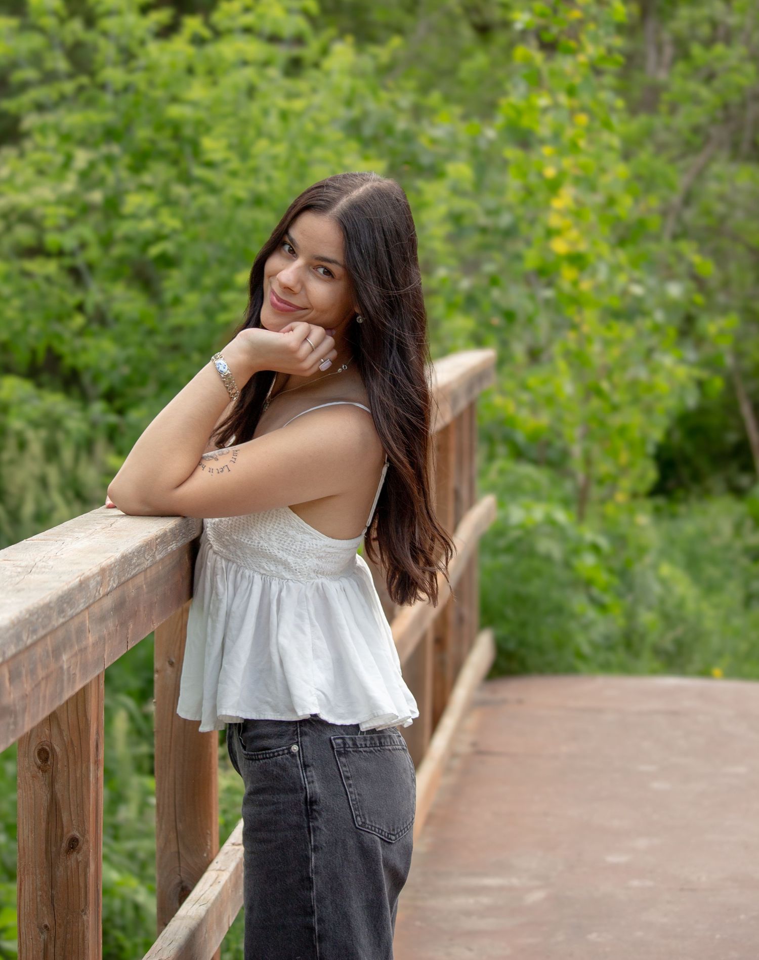 Young woman portrait session posing on a bridge surrounded by beautiful greenery.