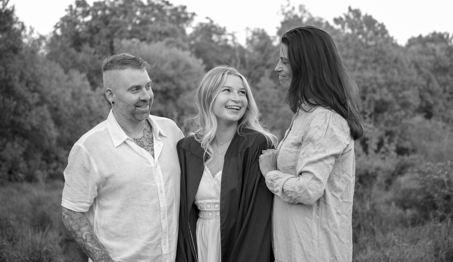 Mom, father and daughter sharing a candid moment during an outdoor family + grad photography session.