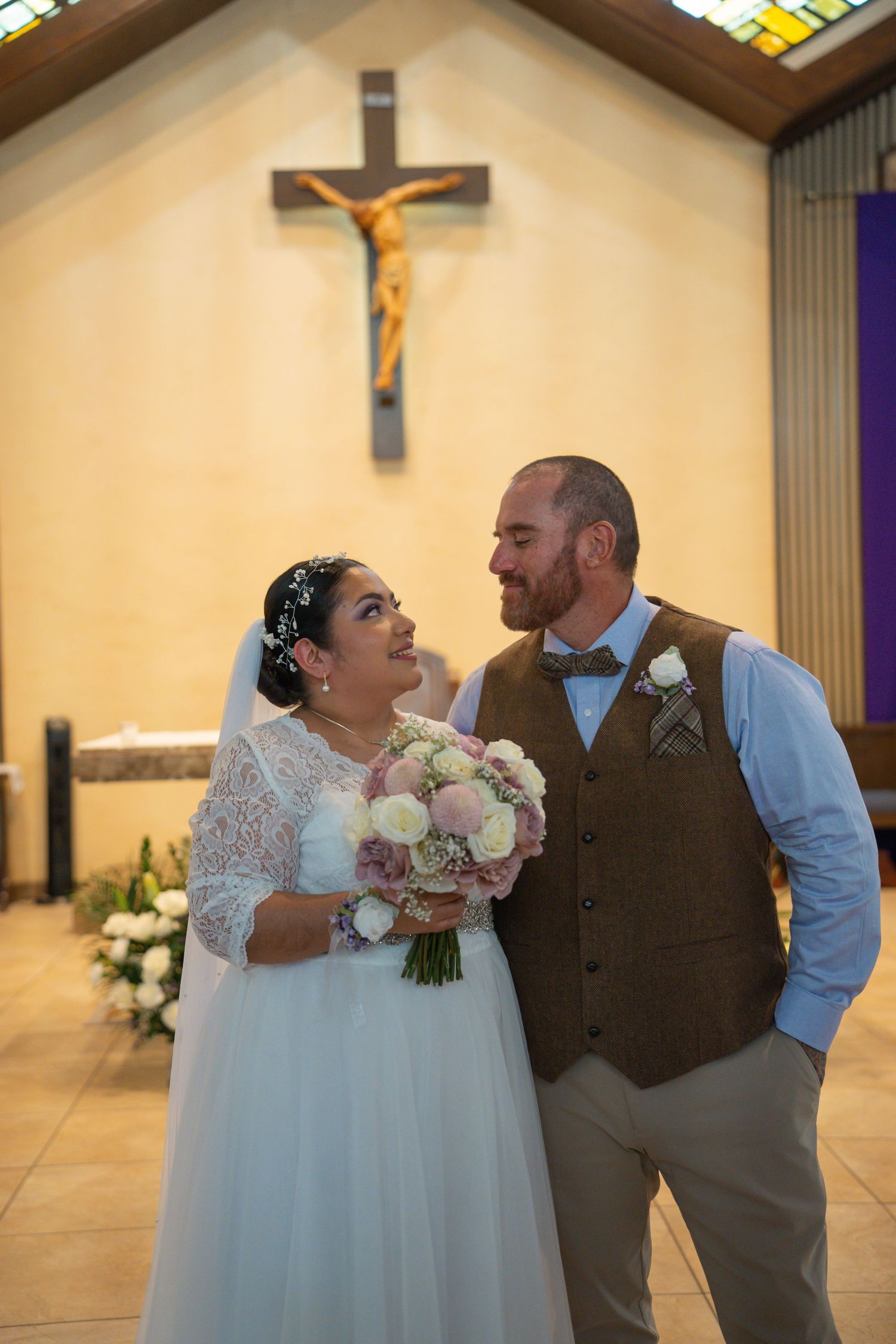 A series of romantic wedding photos showing tender moments between newlyweds inside a church with a crucifix in the background.