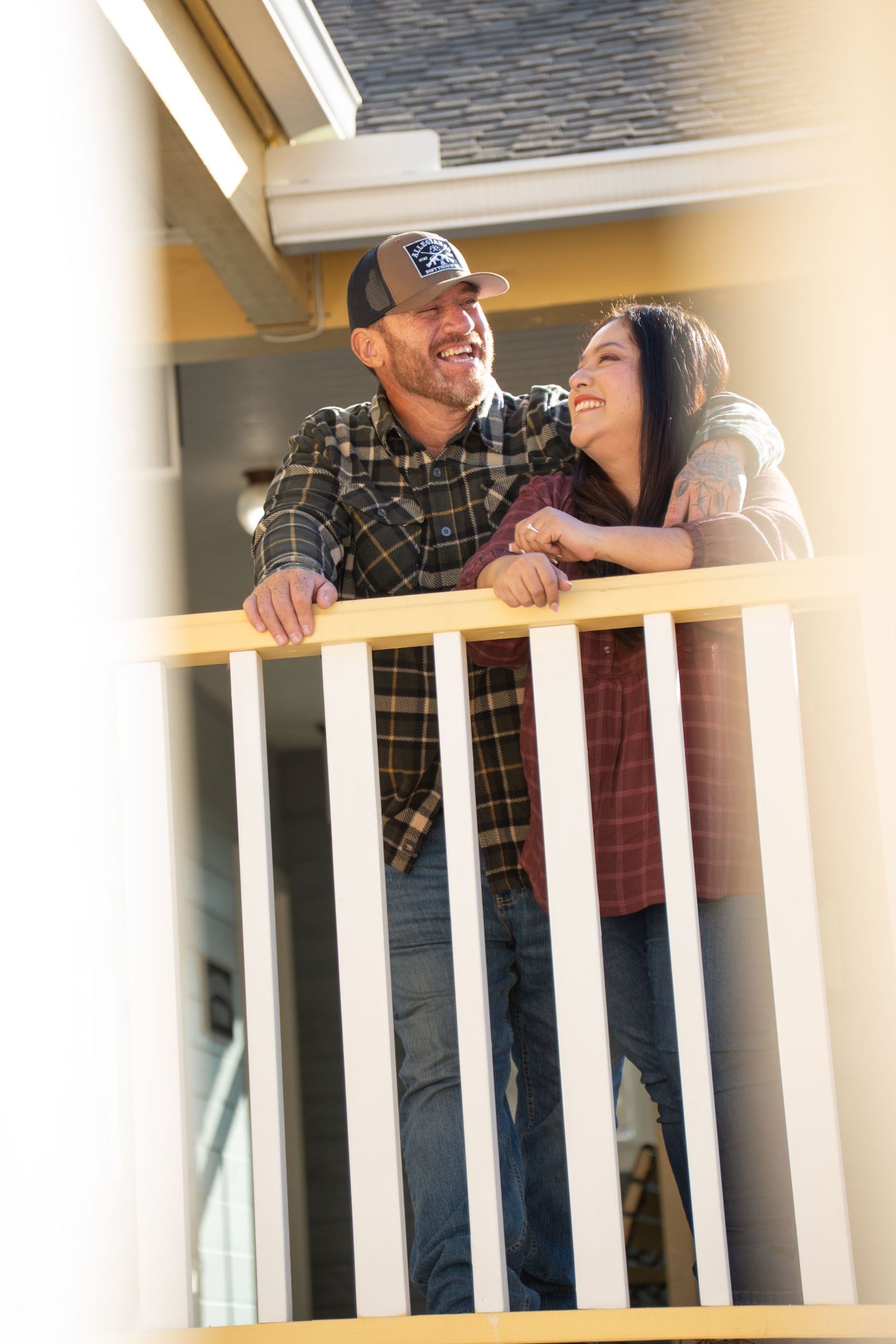 Couple sharing a romantic moment while leaning on white indoor railing.