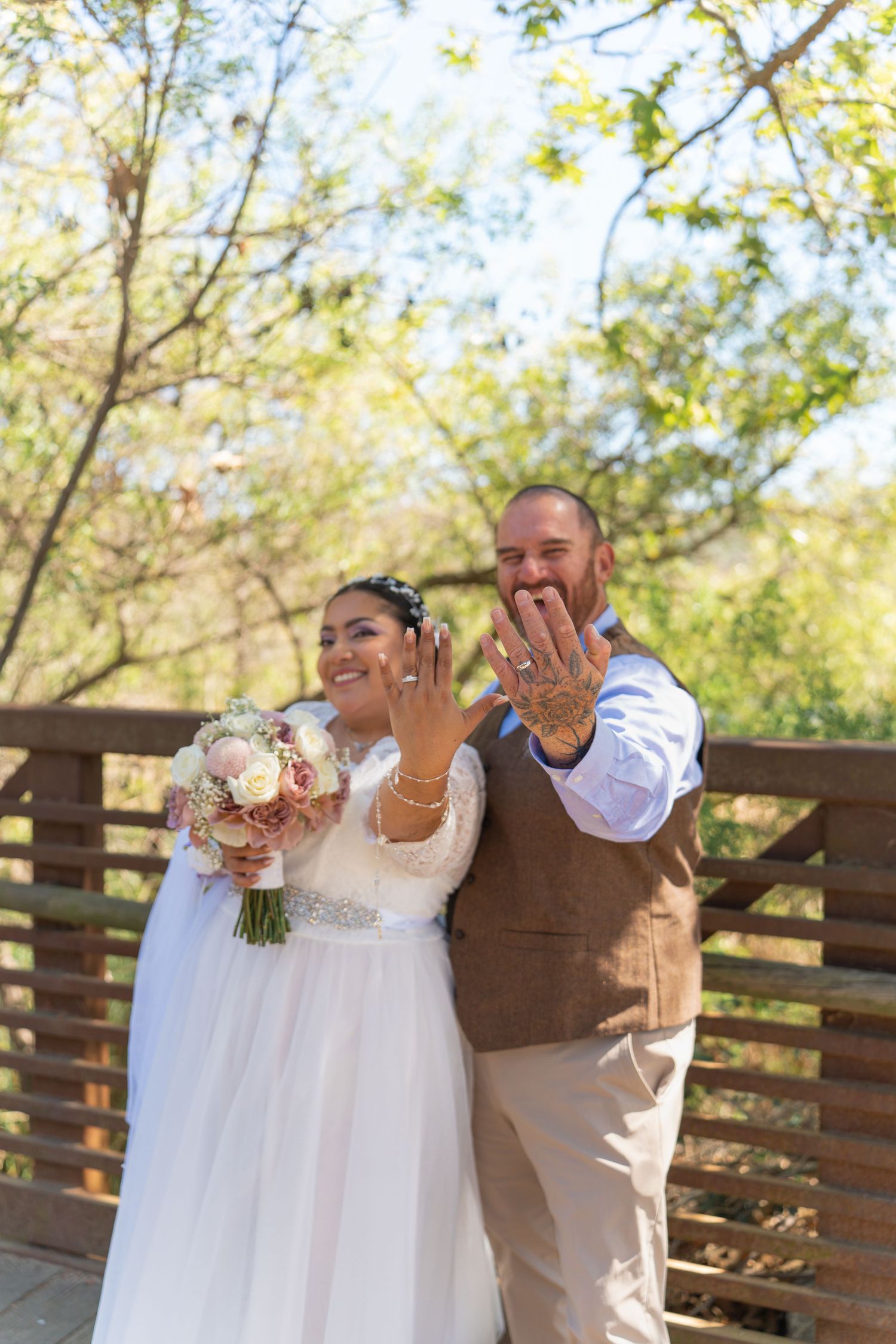 A couple in wedding attire sharing a romantic moment on a wooden deck surrounded by autumn trees.