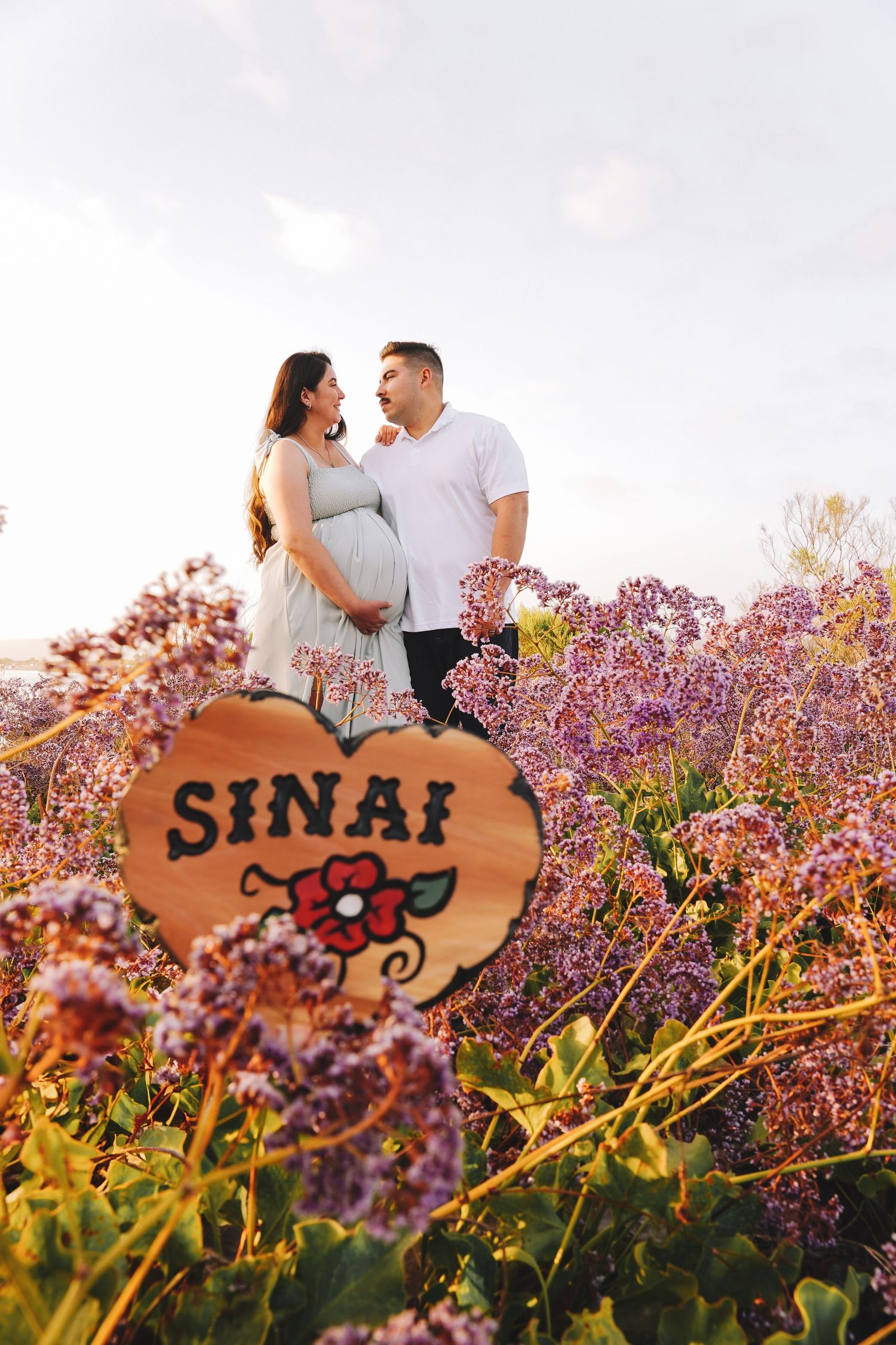 A couple shares a romantic moment in a blooming lavender field with a wooden Sinai sign visible in the background.