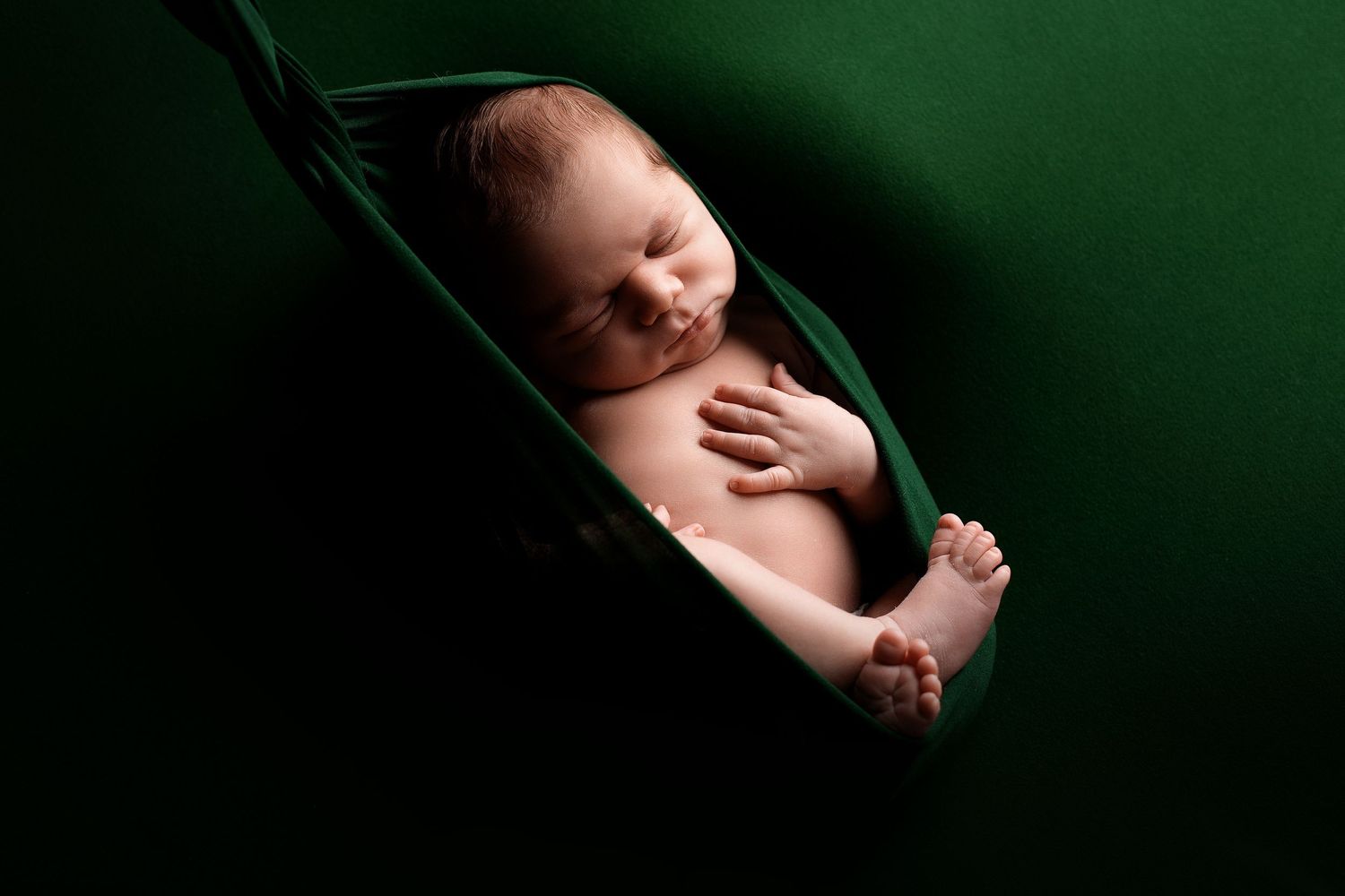 Jaundzimušo fotosesija Rīgā studijā, gulošs mazulis maigā gaismā.