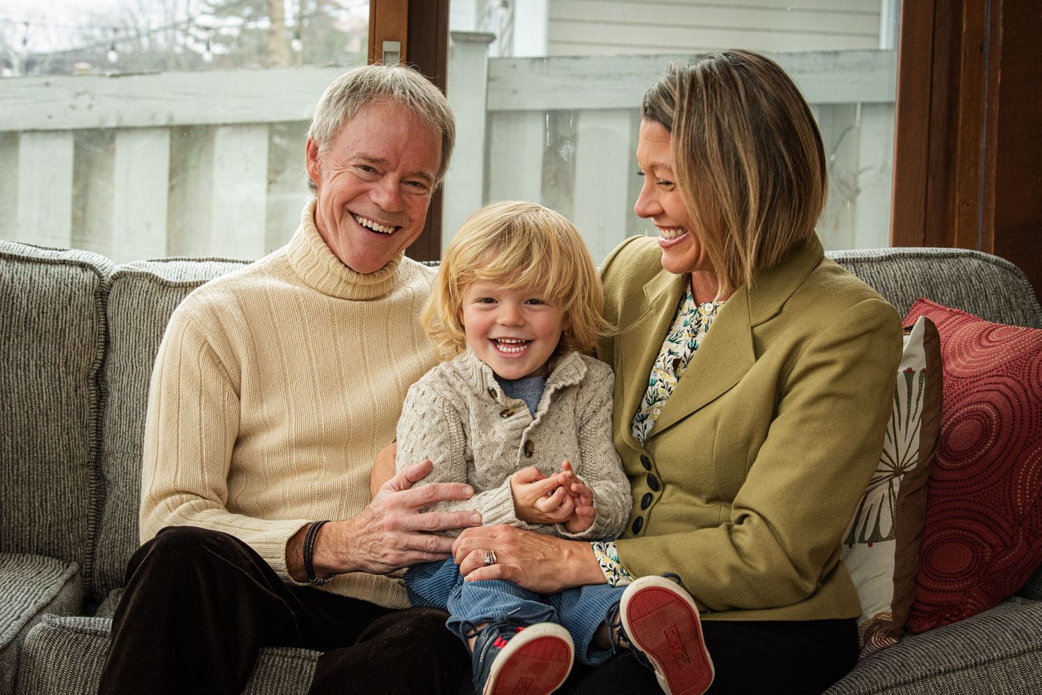 A family shares joyful moments together on a comfortable couch indoors.