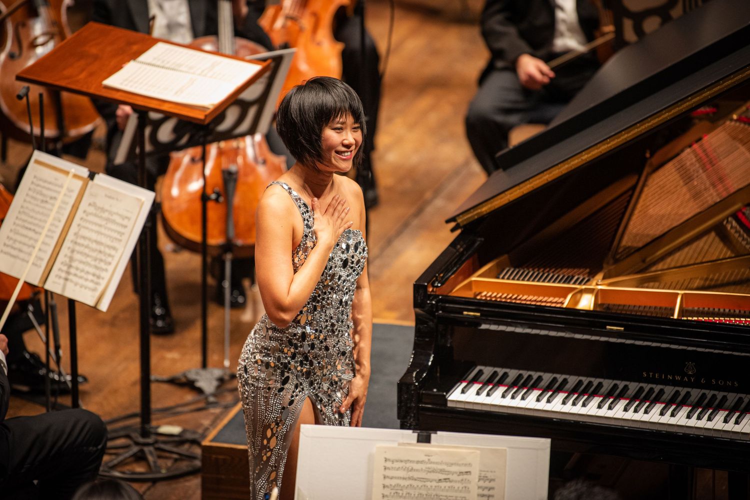 Concert hall performance featuring grand piano and orchestra setup.