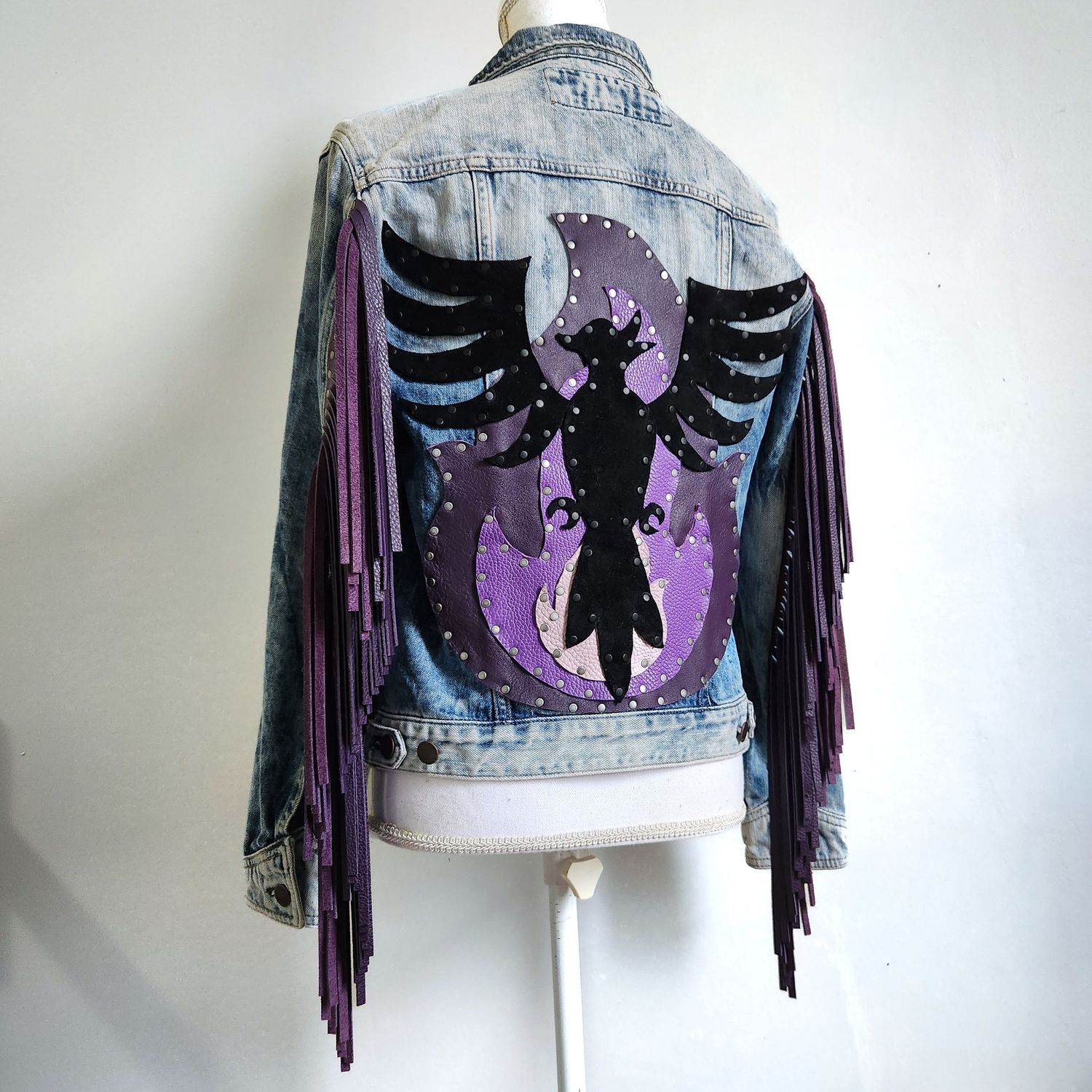 Custom painted denim jacket with purple phoenix design, black studs, and purple leather fringe on the back.
